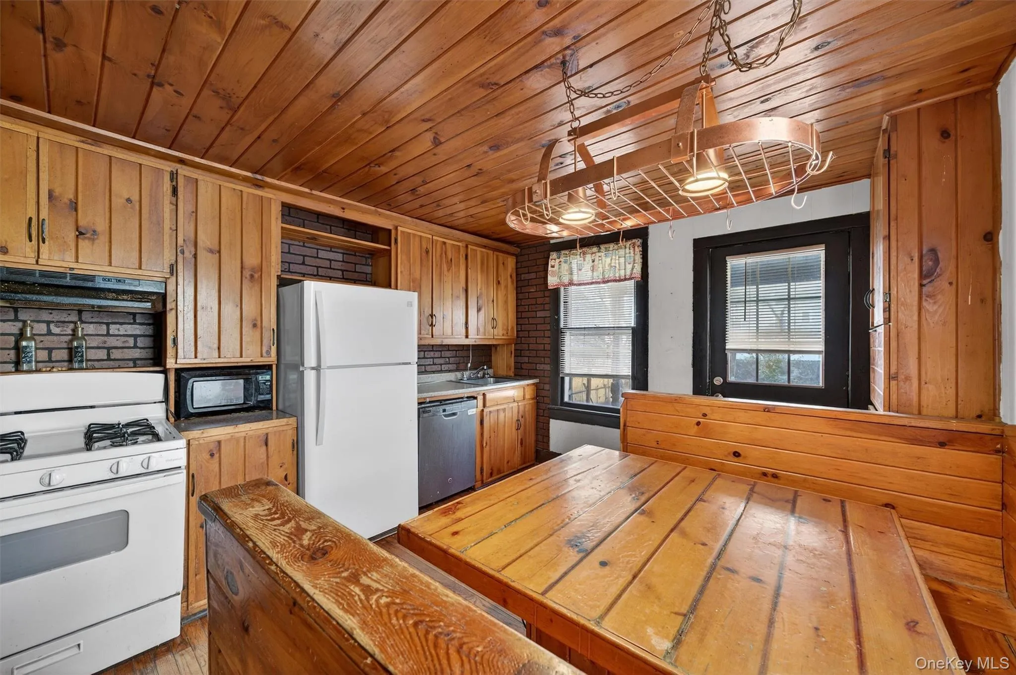 Kitchen with white appliances, open shelves, brown cabinets, wood ceiling, and under cabinet range hood Kitchen with white appliances, open shelves, brown cabinets, wood ceiling, and under cabinet range hood