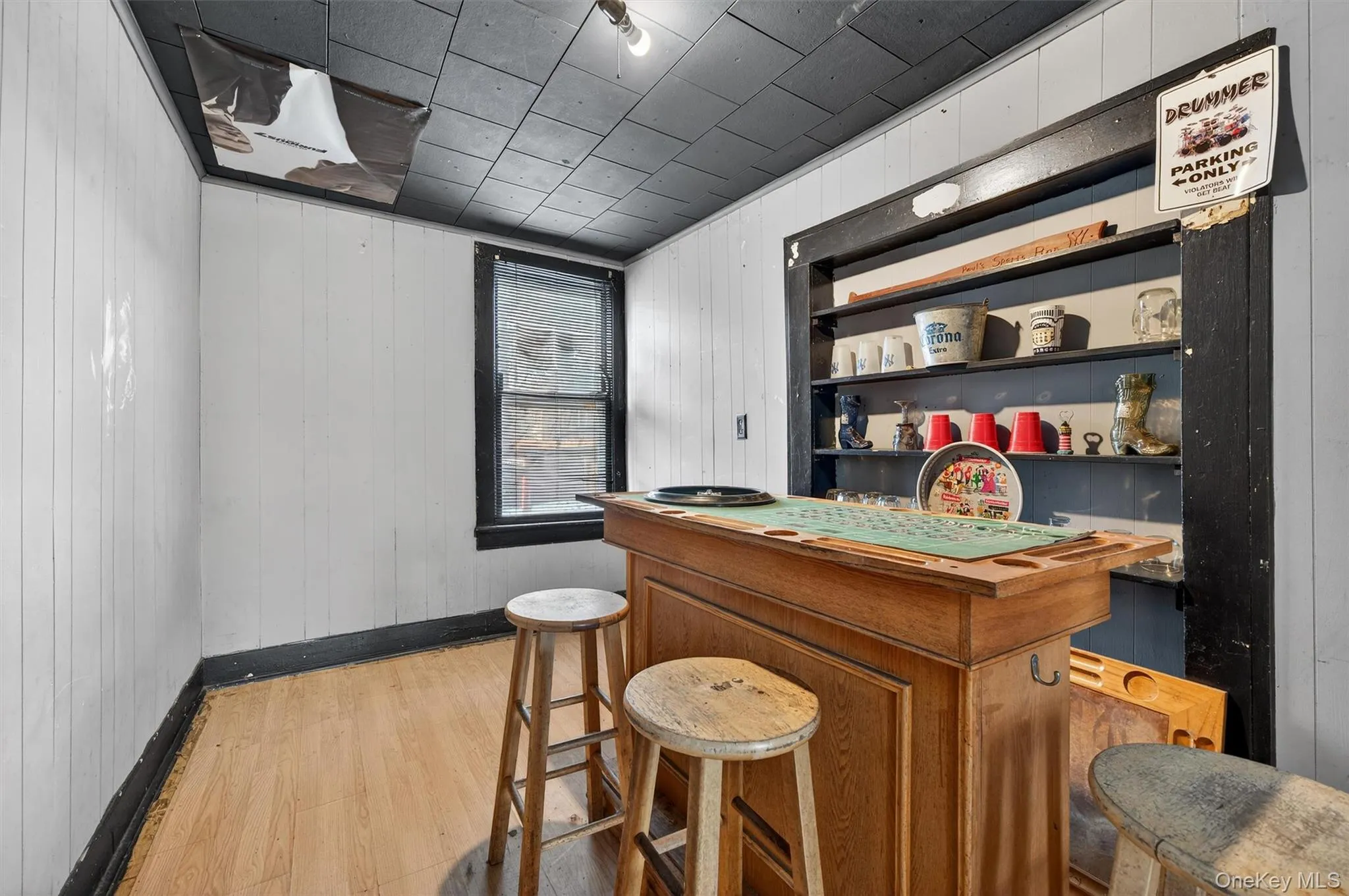 Indoor dry bar featuring wood walls, light wood-style flooring, and open shelves Indoor dry bar featuring wood walls, light wood-style flooring, and open shelves