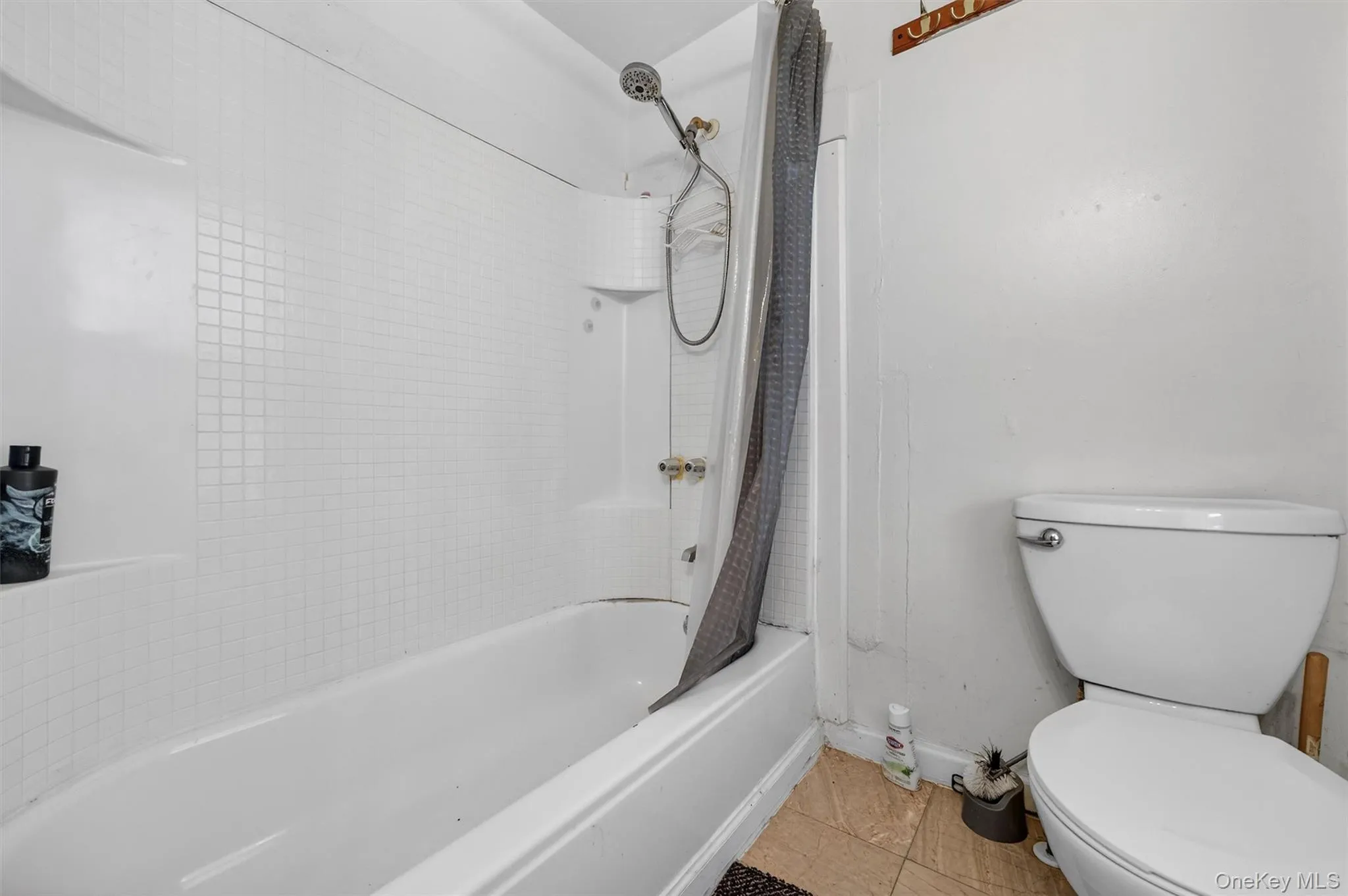 Full bath featuring shower / tub combo with curtain and light tile patterned floors Full bath featuring shower / tub combo with curtain and light tile patterned floors