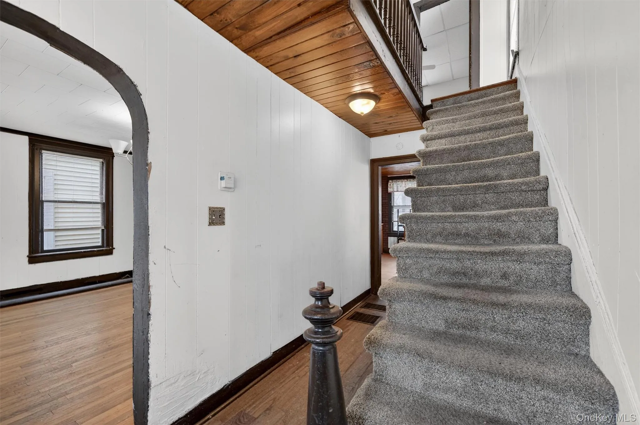 Stairway featuring arched walkways, wood finished floors, and wooden walls Stairway featuring arched walkways, wood finished floors, and wooden walls