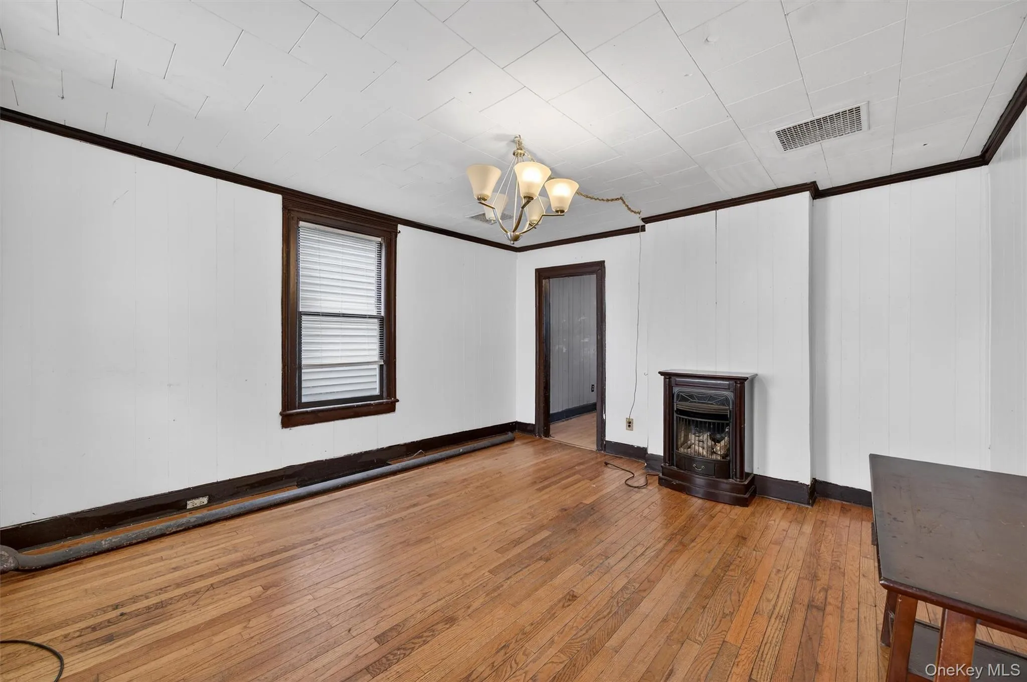 Unfurnished living room featuring wood-type flooring, a chandelier, a fireplace, and ornamental molding Unfurnished living room featuring wood-type flooring, a chandelier, a fireplace, and ornamental molding