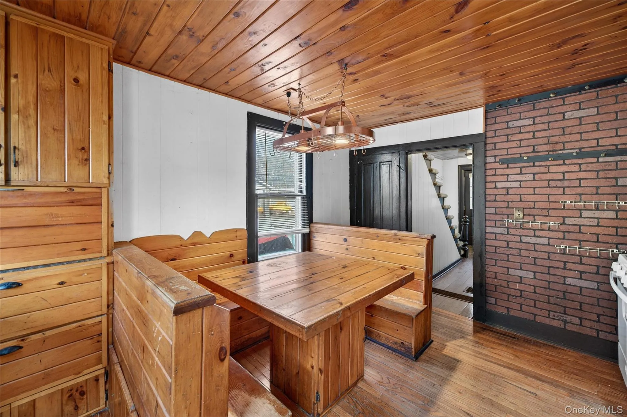 Dining area featuring wood ceiling, brick wall, stairs, light wood-style flooring, and wooden walls Dining area featuring wood ceiling, brick wall, stairs, light wood-style flooring, and wooden walls