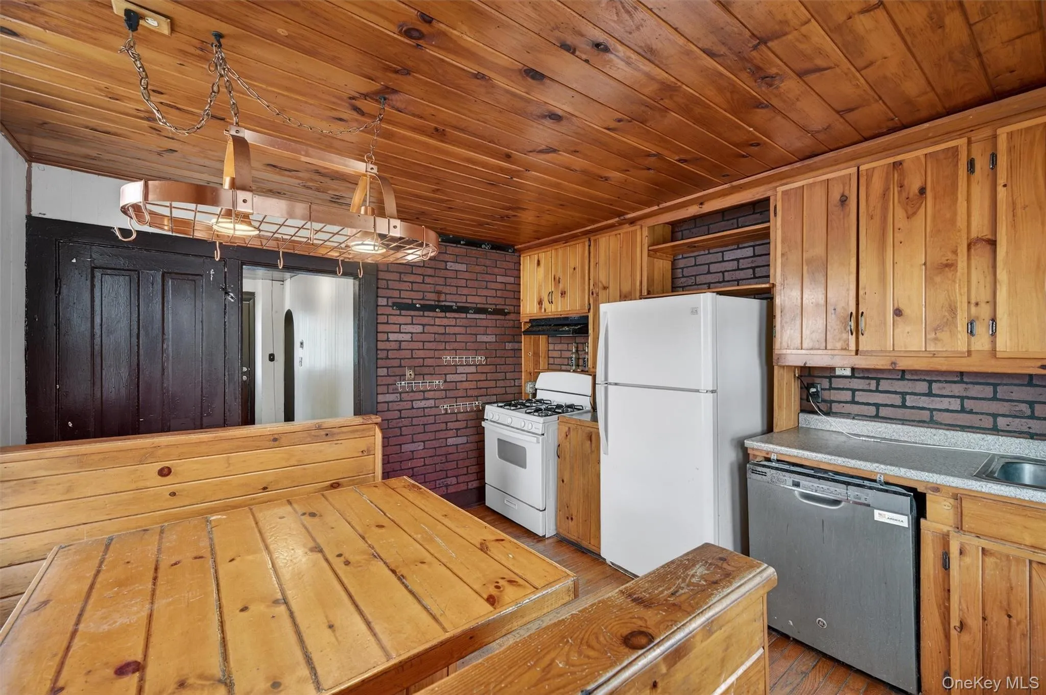 Kitchen featuring open shelves, wooden ceiling, white appliances, light countertops, and brick wall Kitchen featuring open shelves, wooden ceiling, white appliances, light countertops, and brick wall