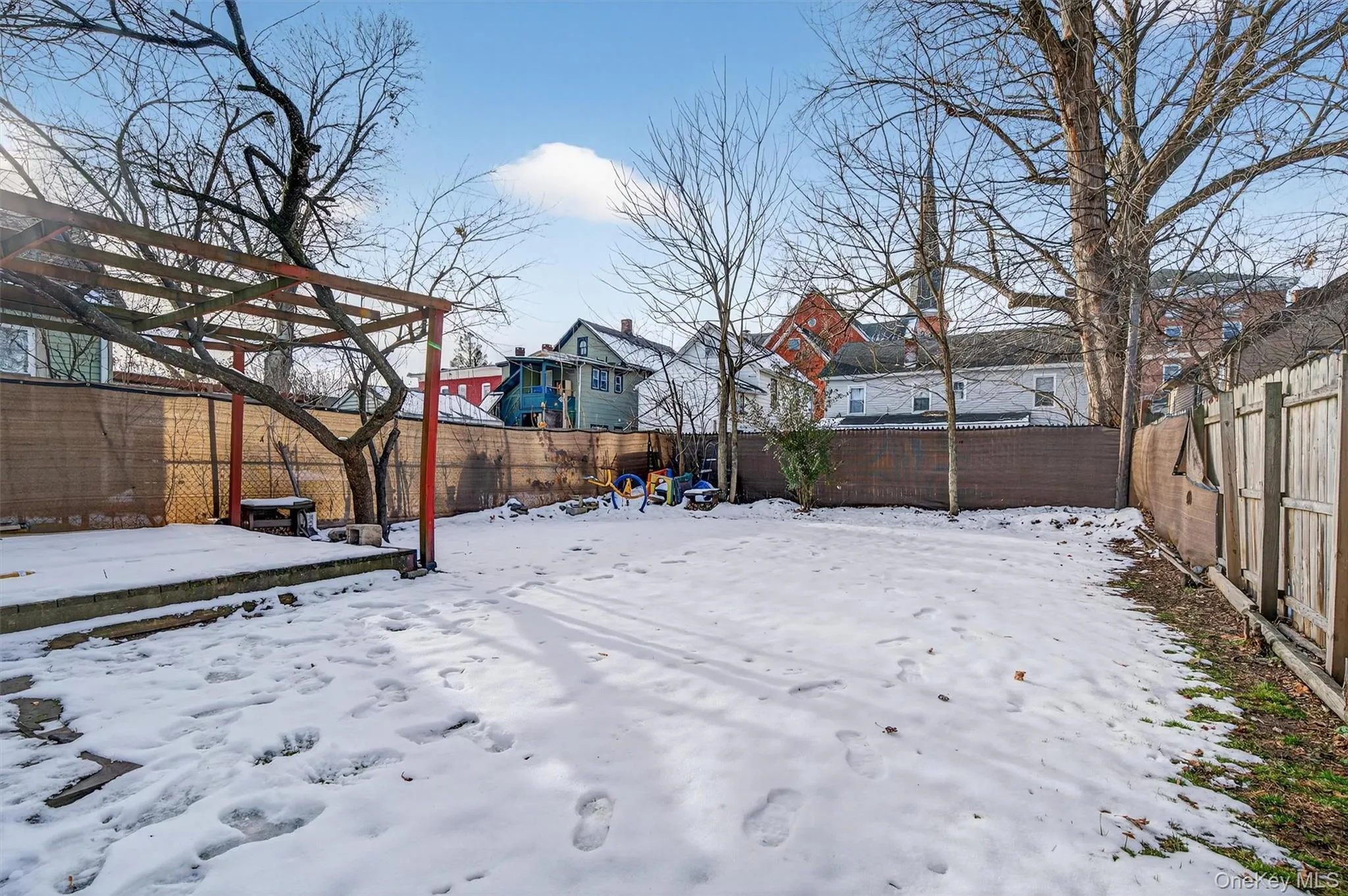 Yard covered in snow with a fenced backyard and a residential view Yard covered in snow with a fenced backyard and a residential view