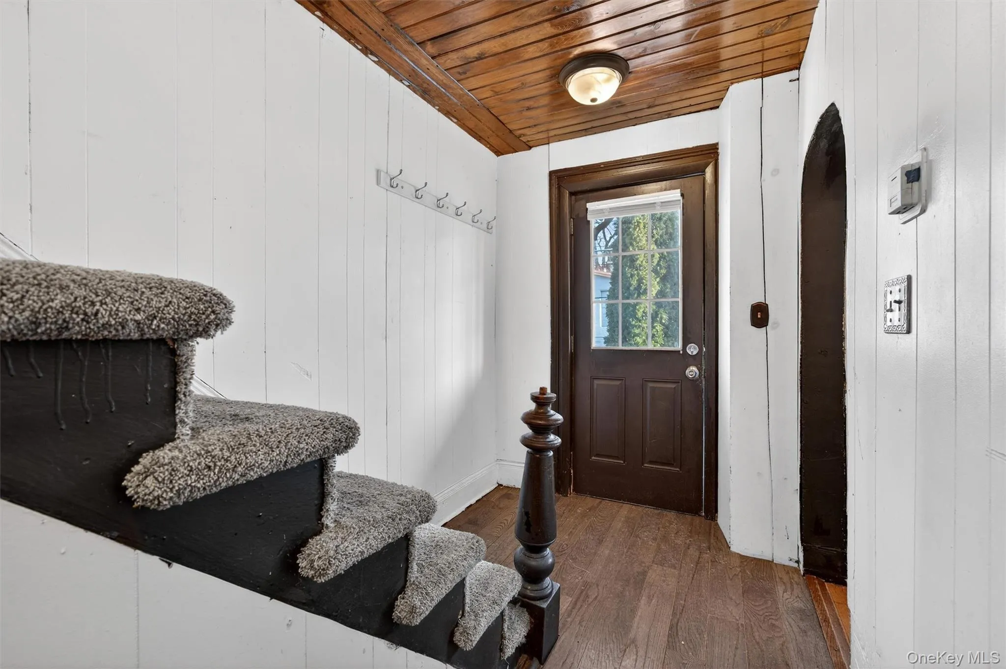 Entryway with dark wood-style flooring, wooden walls, wooden ceiling, and arched walkways Entryway with dark wood-style flooring, wooden walls, wooden ceiling, and arched walkways