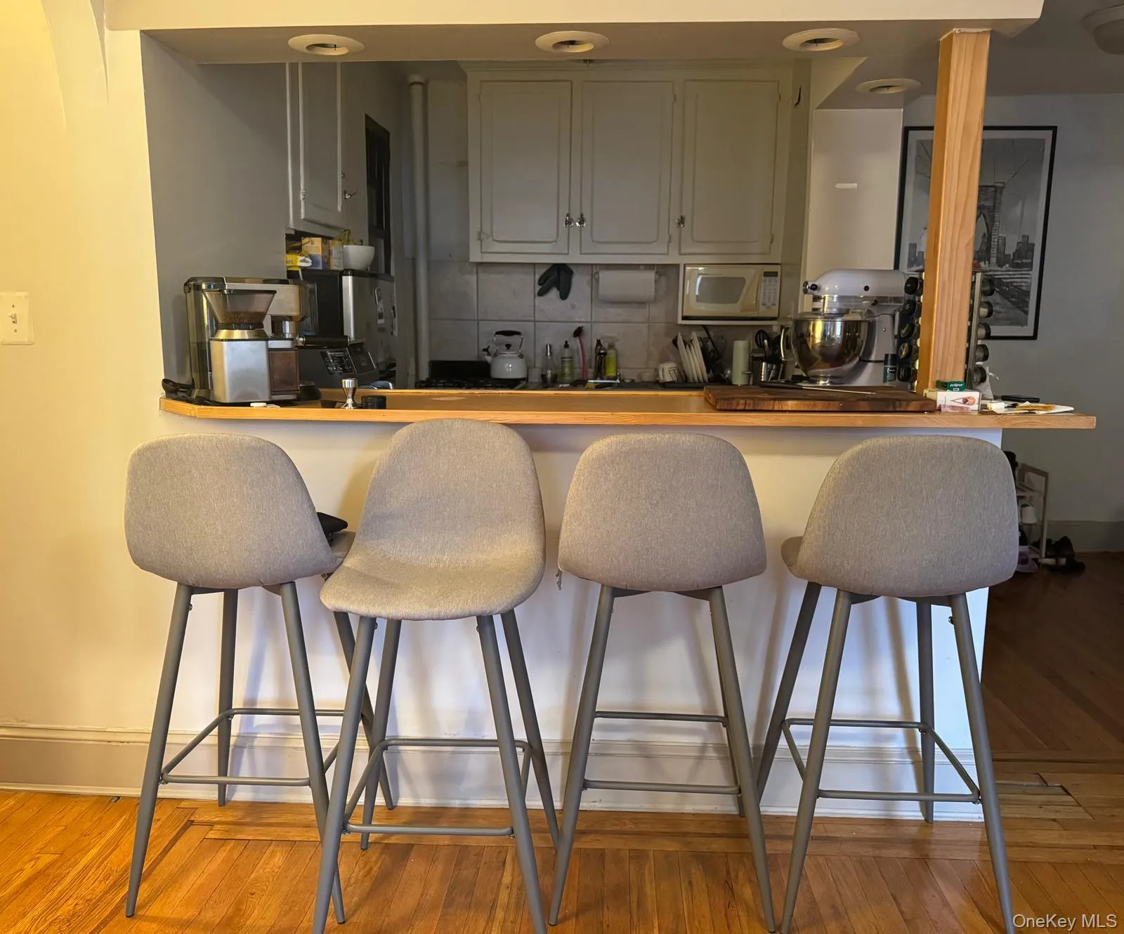 Kitchen featuring decorative backsplash, a breakfast bar area, white microwave, butcher block countertops, and wood finished floors Kitchen featuring decorative backsplash, a breakfast bar area, white microwave, butcher block countertops, and wood finished floors