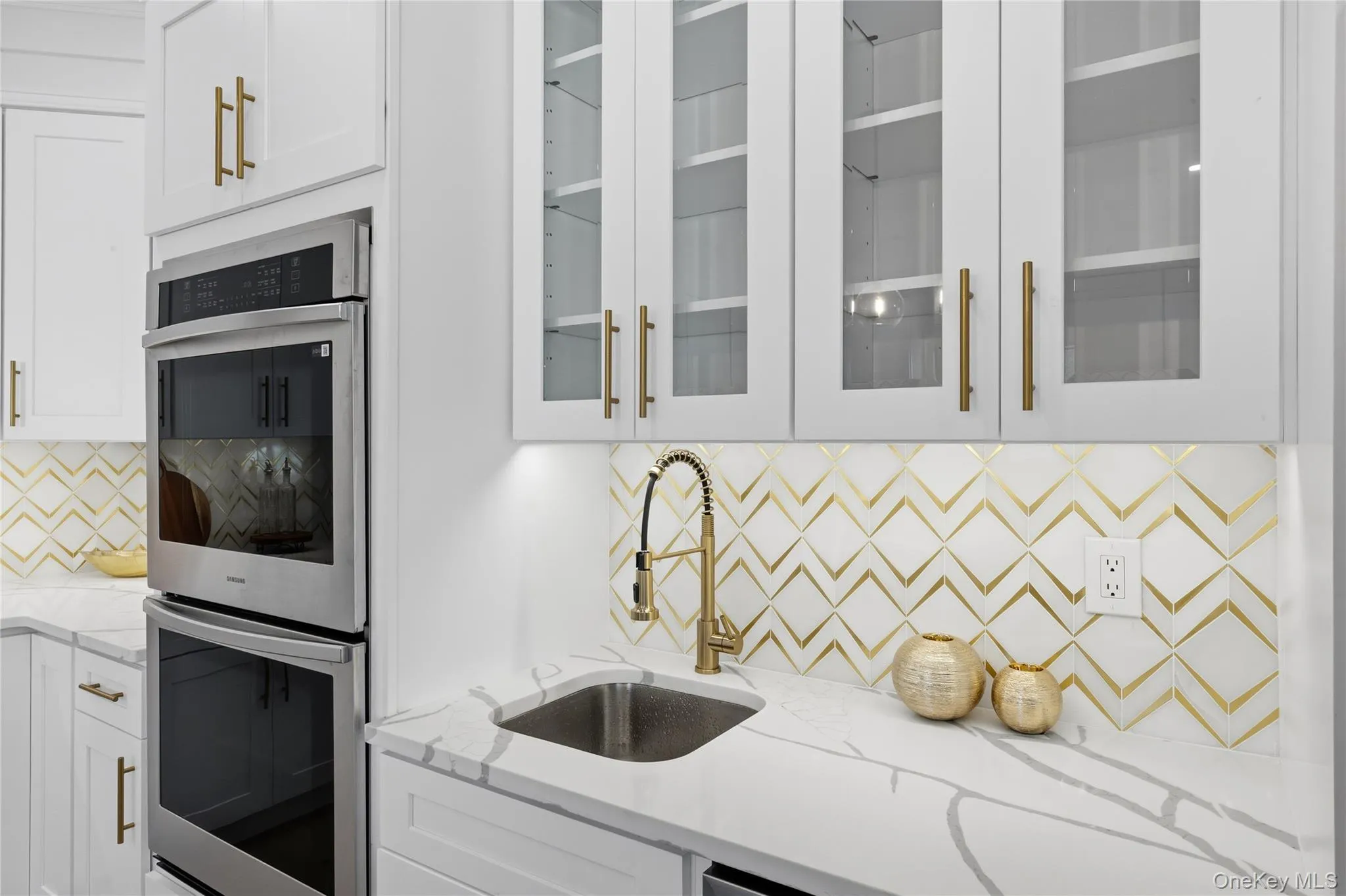 Kitchen featuring stainless steel double oven, backsplash, light stone counters, and white cabinetry Kitchen featuring stainless steel double oven, backsplash, light stone counters, and white cabinetry