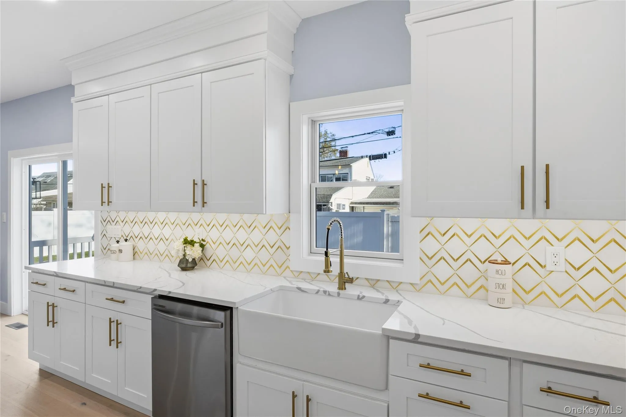 Kitchen featuring stainless steel dishwasher, white cabinets, and light stone countertops Kitchen featuring stainless steel dishwasher, white cabinets, and light stone countertops