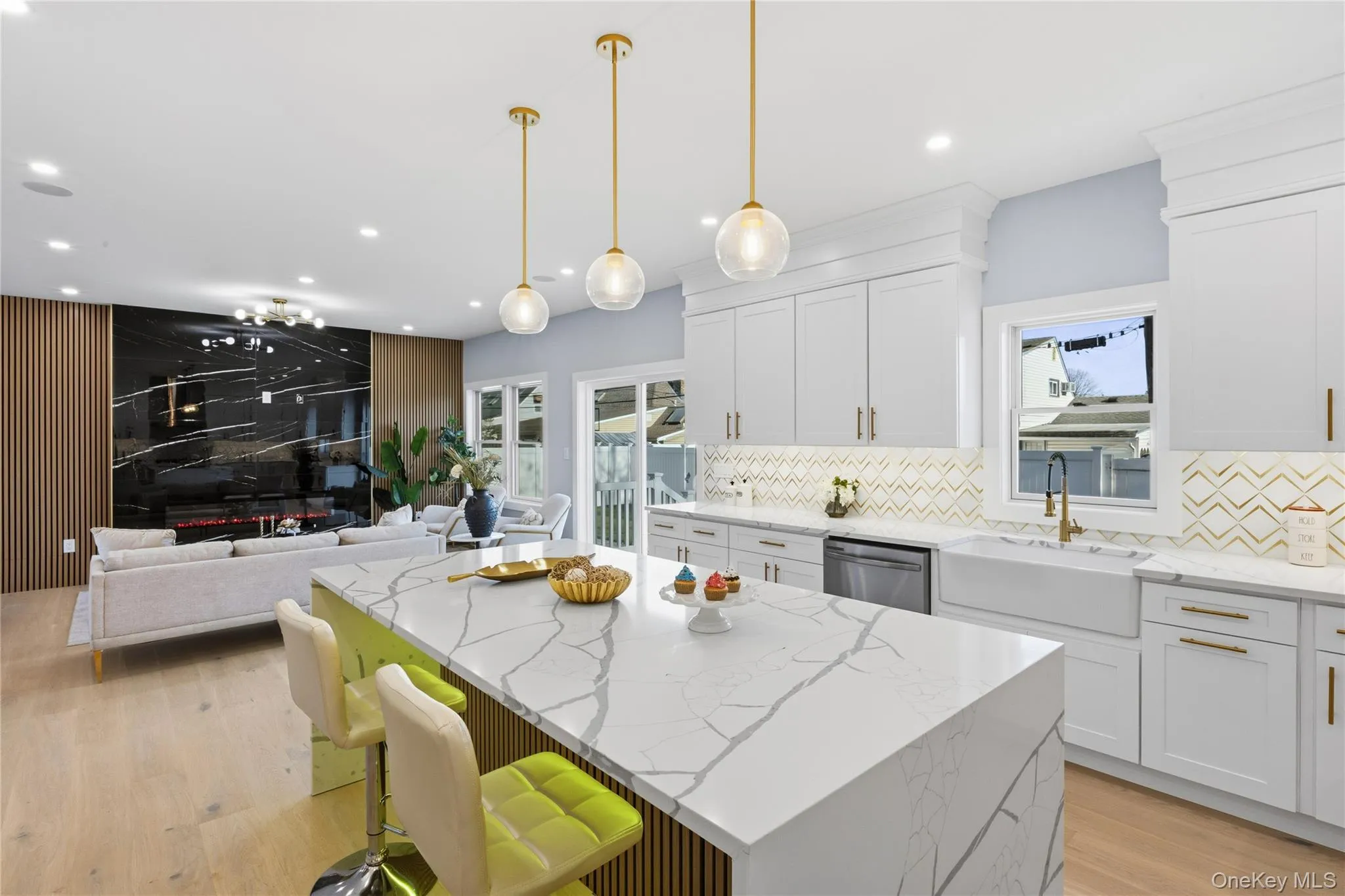Kitchen featuring light stone counters, open floor plan, white cabinets, a kitchen island, and hanging light fixtures Kitchen featuring light stone counters, open floor plan, white cabinets, a kitchen island, and hanging light fixtures
