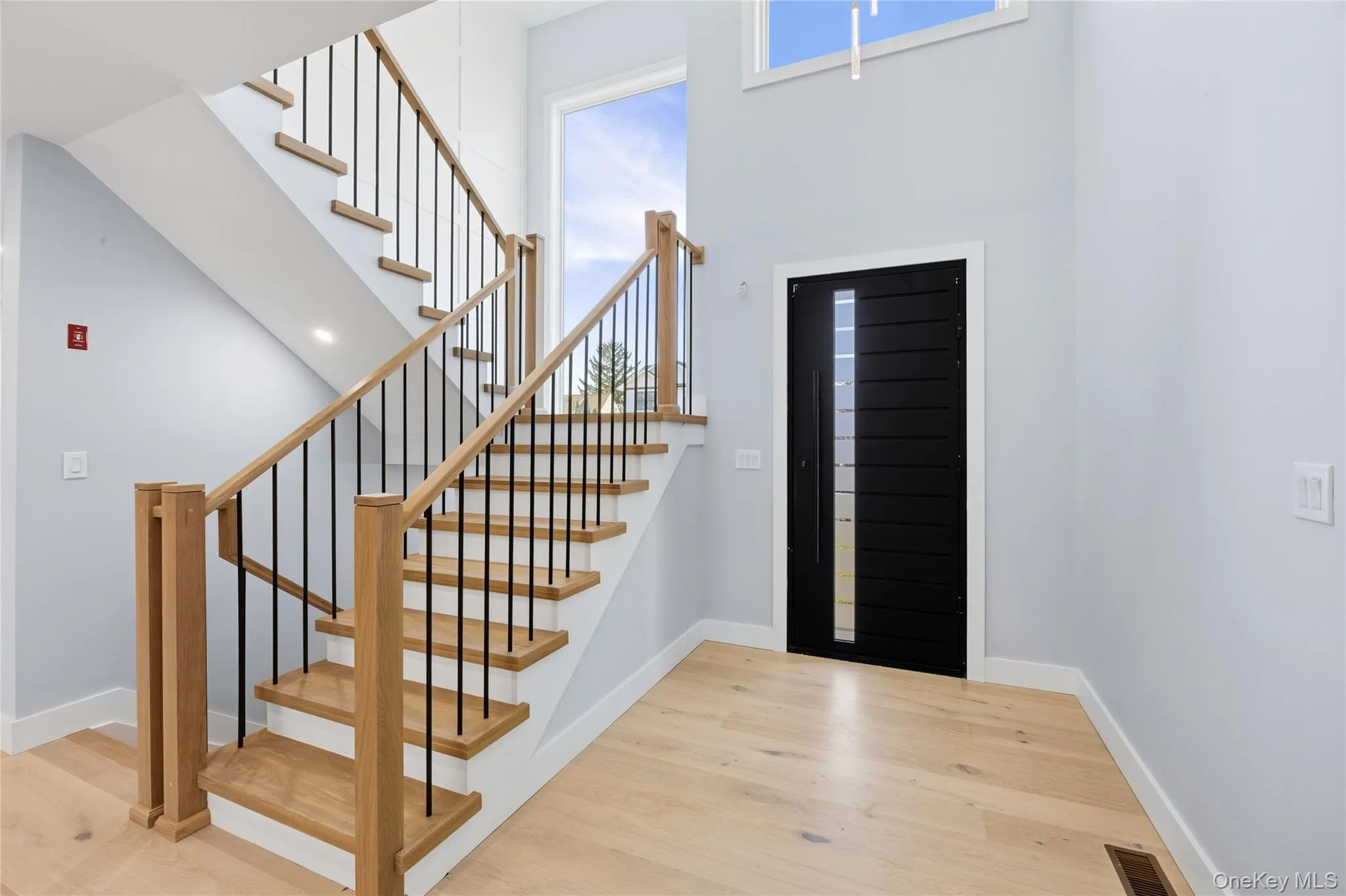 Foyer entrance with a high ceiling, light wood finished floors, and stairs Foyer entrance with a high ceiling, light wood finished floors, and stairs