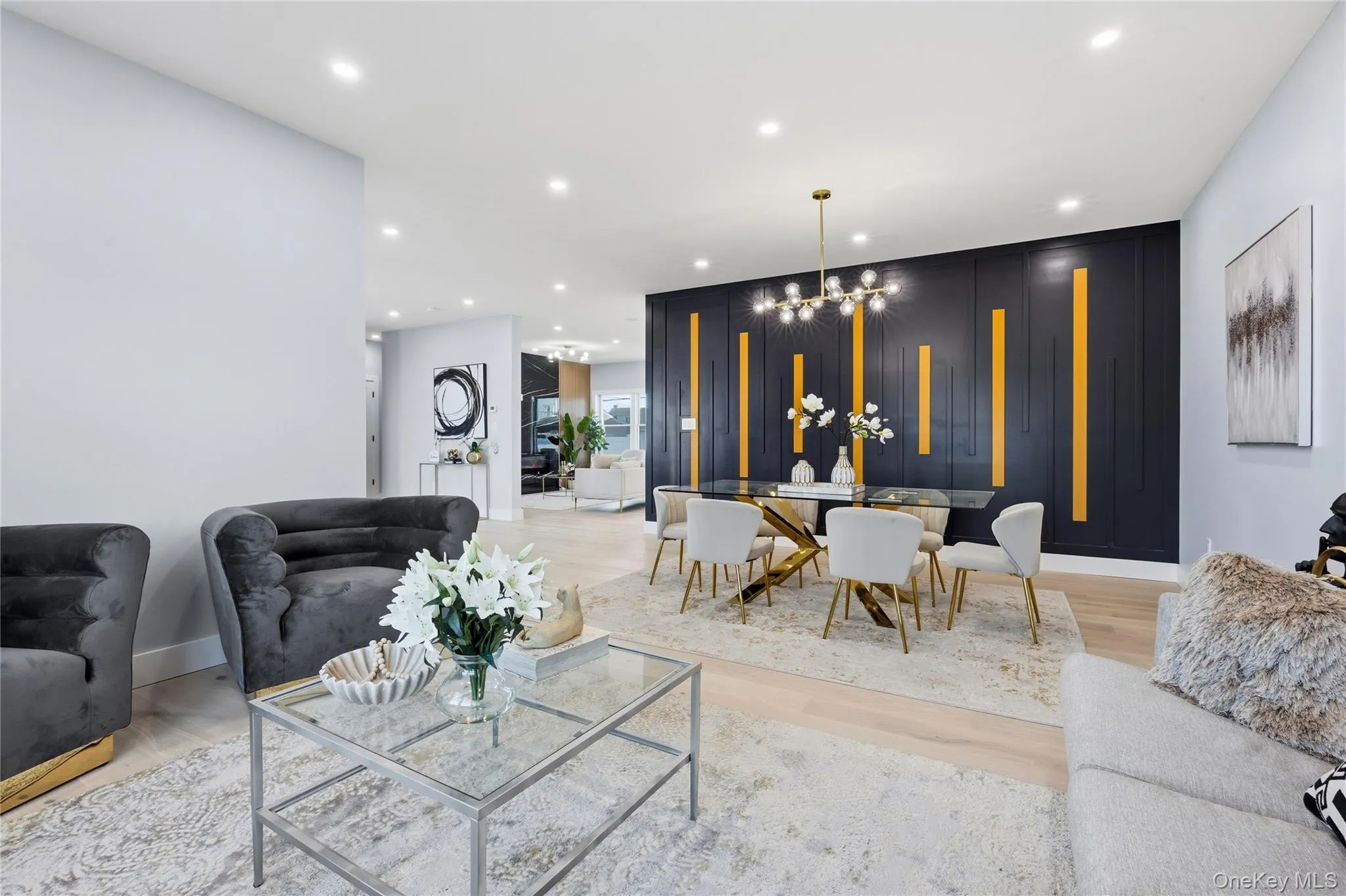 Living room with a chandelier, recessed lighting, light wood-type flooring, and an accent wall Living room with a chandelier, recessed lighting, light wood-type flooring, and an accent wall