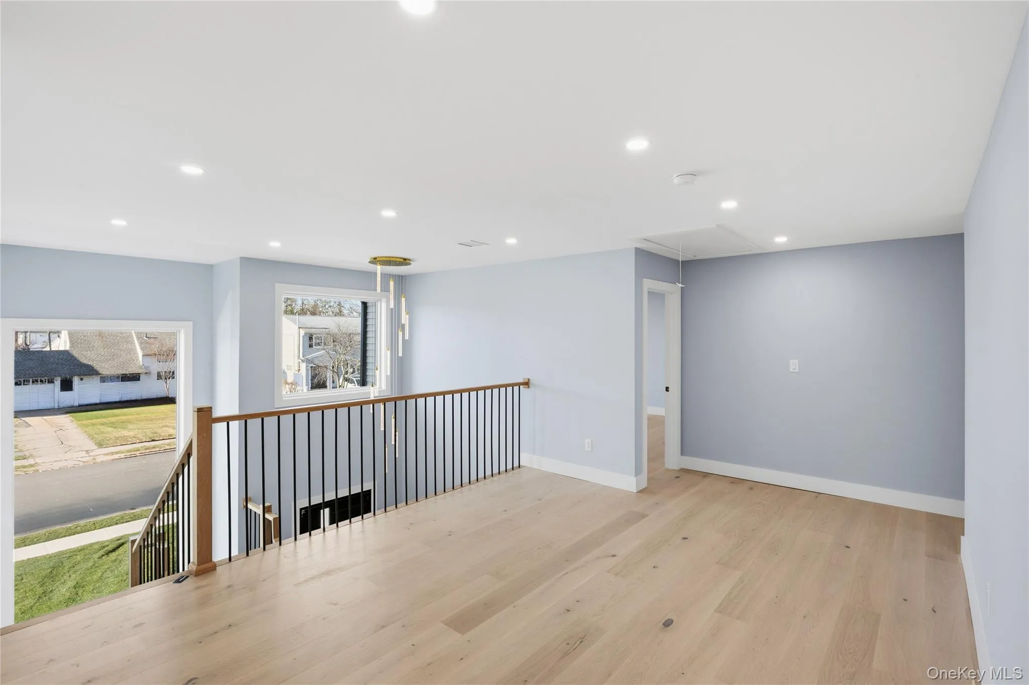 Empty room with light wood-style floors, attic access, and recessed lighting Empty room with light wood-style floors, attic access, and recessed lighting