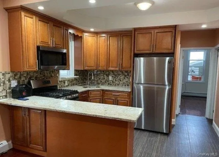 Kitchen featuring brown cabinets, light stone countertops, appliances with stainless steel finishes, and recessed lighting Kitchen featuring brown cabinets, light stone countertops, appliances with stainless steel finishes, and recessed lighting