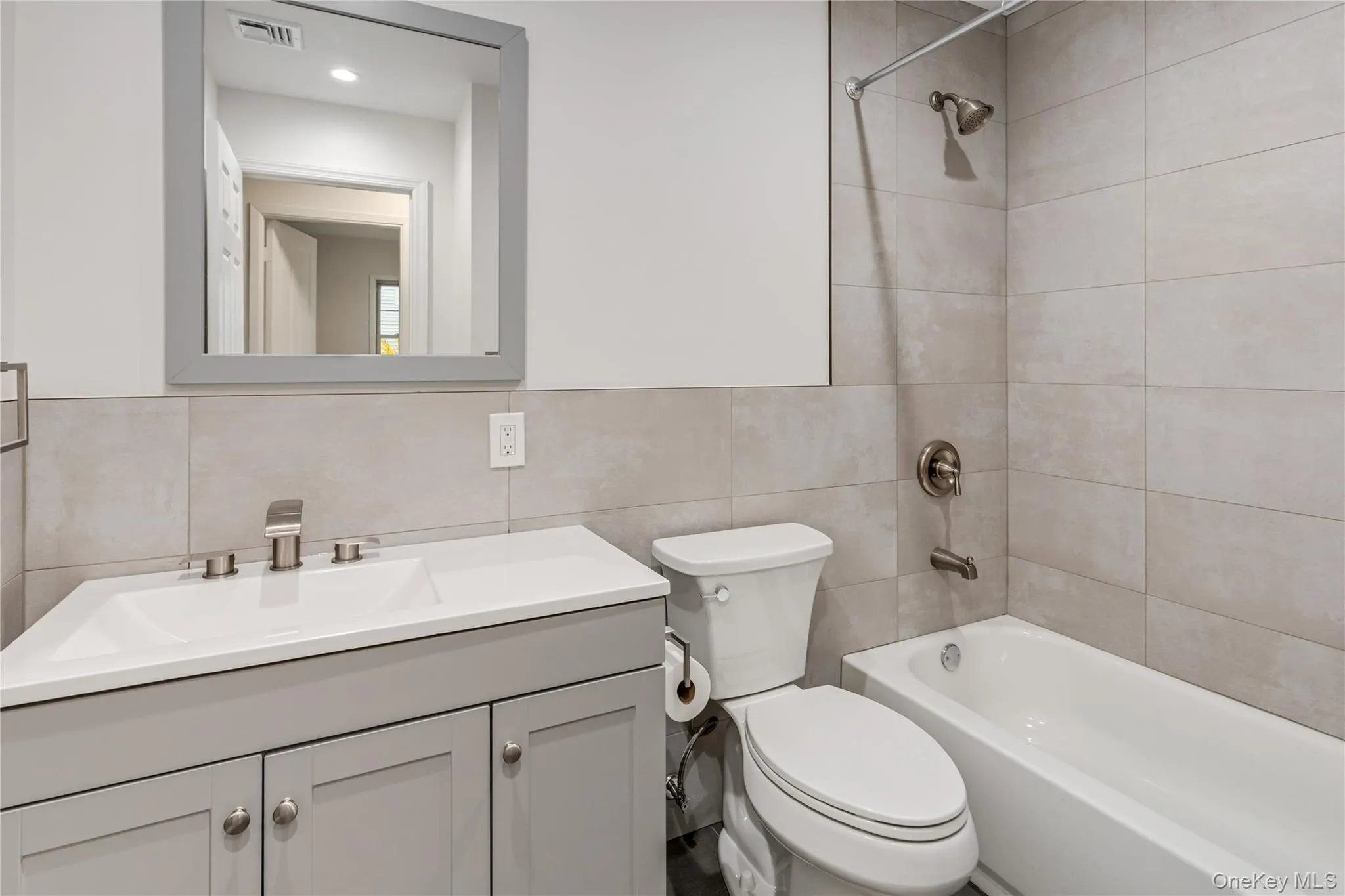 Full bath featuring vanity, shower / washtub combination, and tile walls Full bath featuring vanity, shower / washtub combination, and tile walls