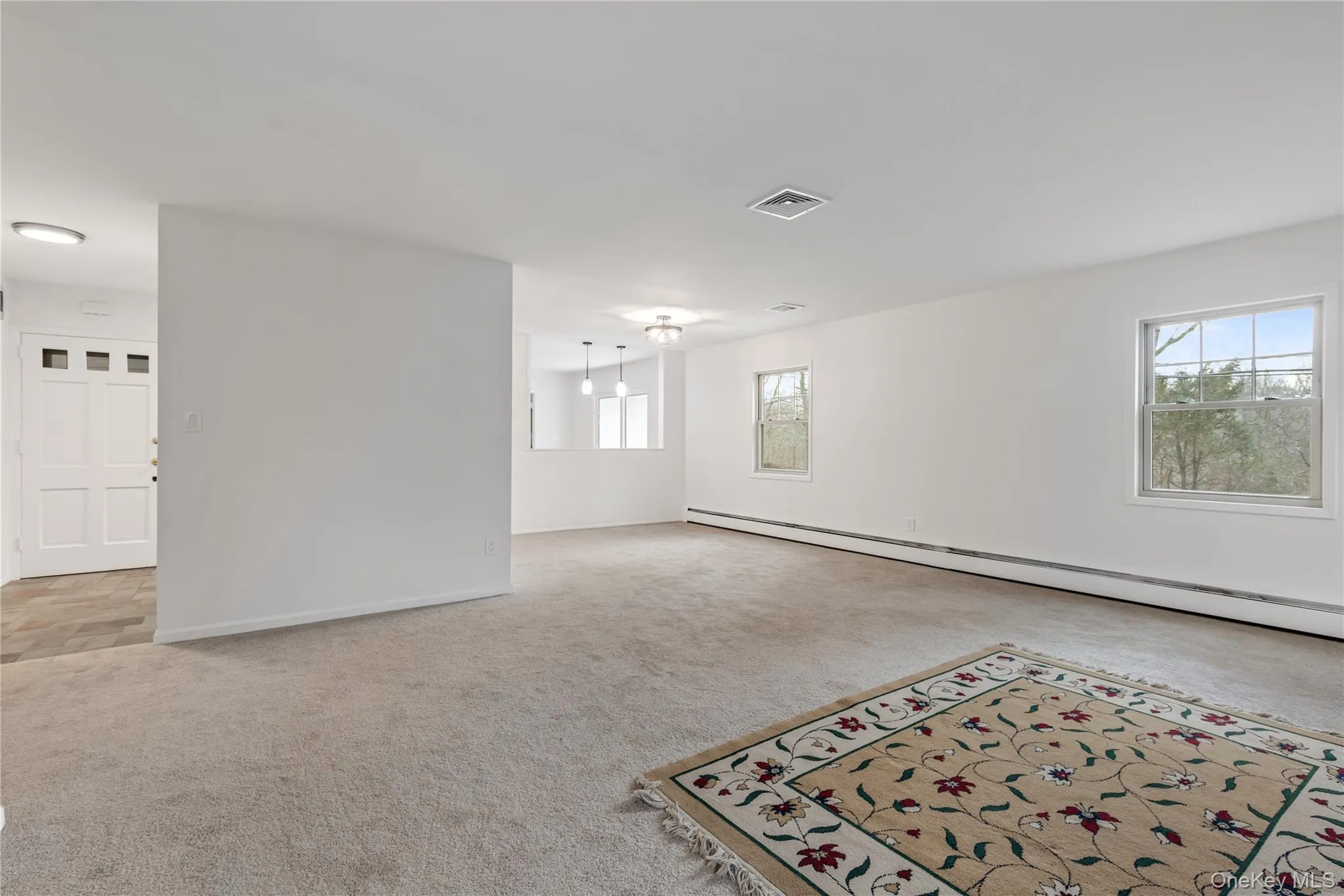 Unfurnished room featuring baseboard heating, light colored carpet, and healthy amount of natural light Unfurnished room featuring baseboard heating, light colored carpet, and healthy amount of natural light