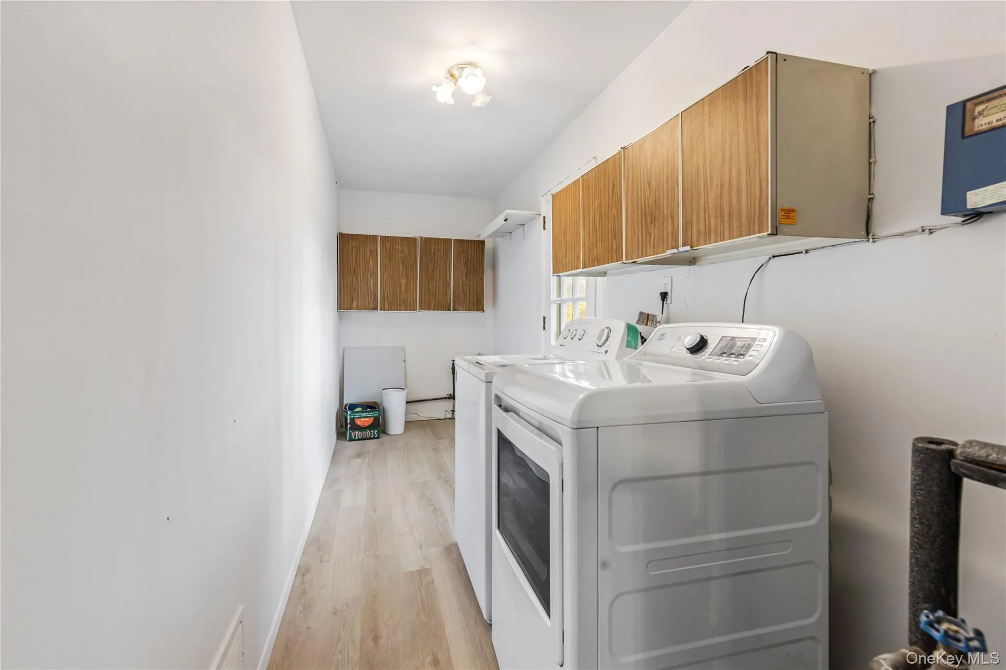 Laundry area featuring light wood-style flooring, washing machine and clothes dryer, and cabinet space Laundry area featuring light wood-style flooring, washing machine and clothes dryer, and cabinet space
