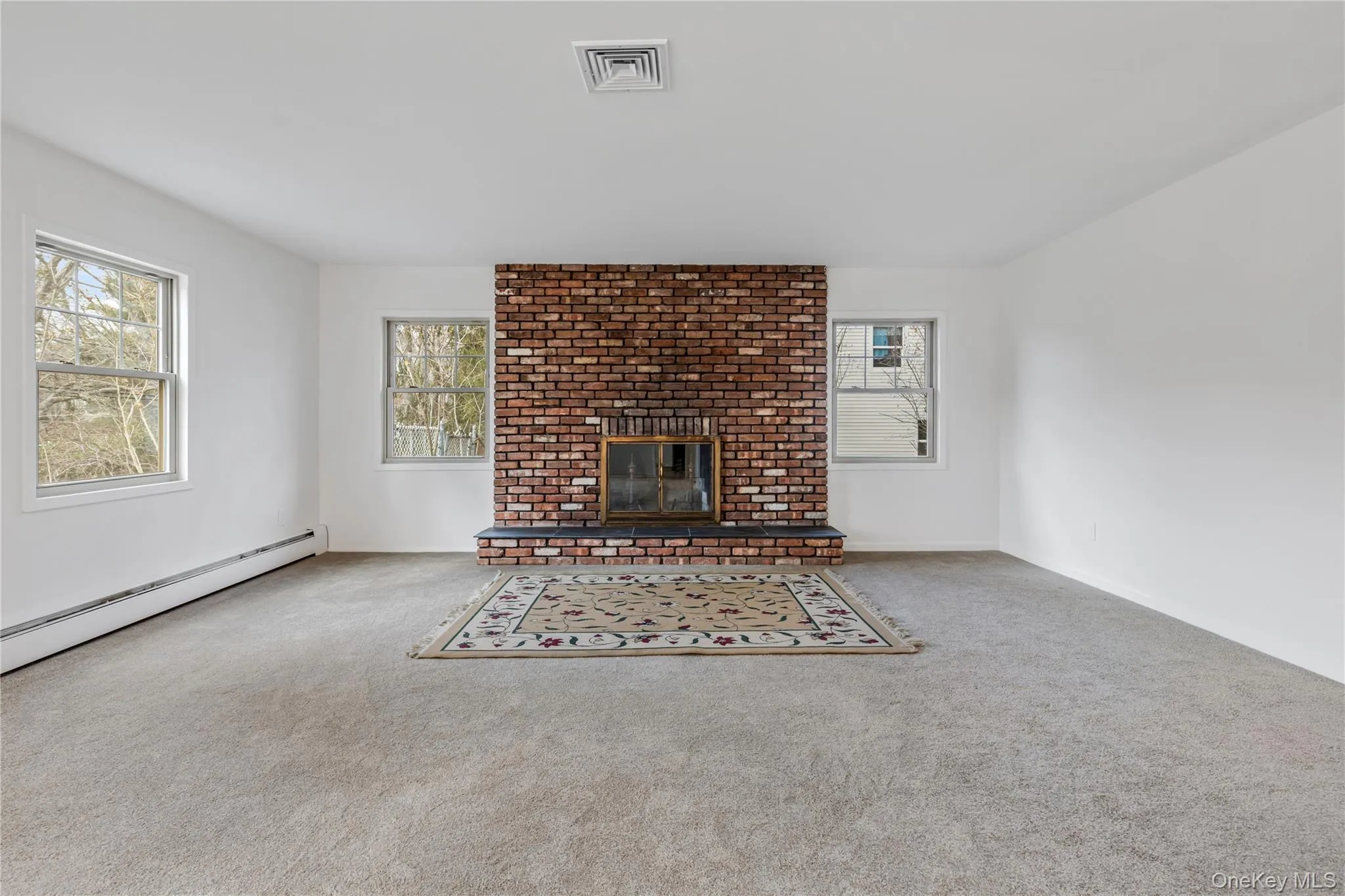 Unfurnished living room with a brick fireplace and carpet floors Unfurnished living room with a brick fireplace and carpet floors