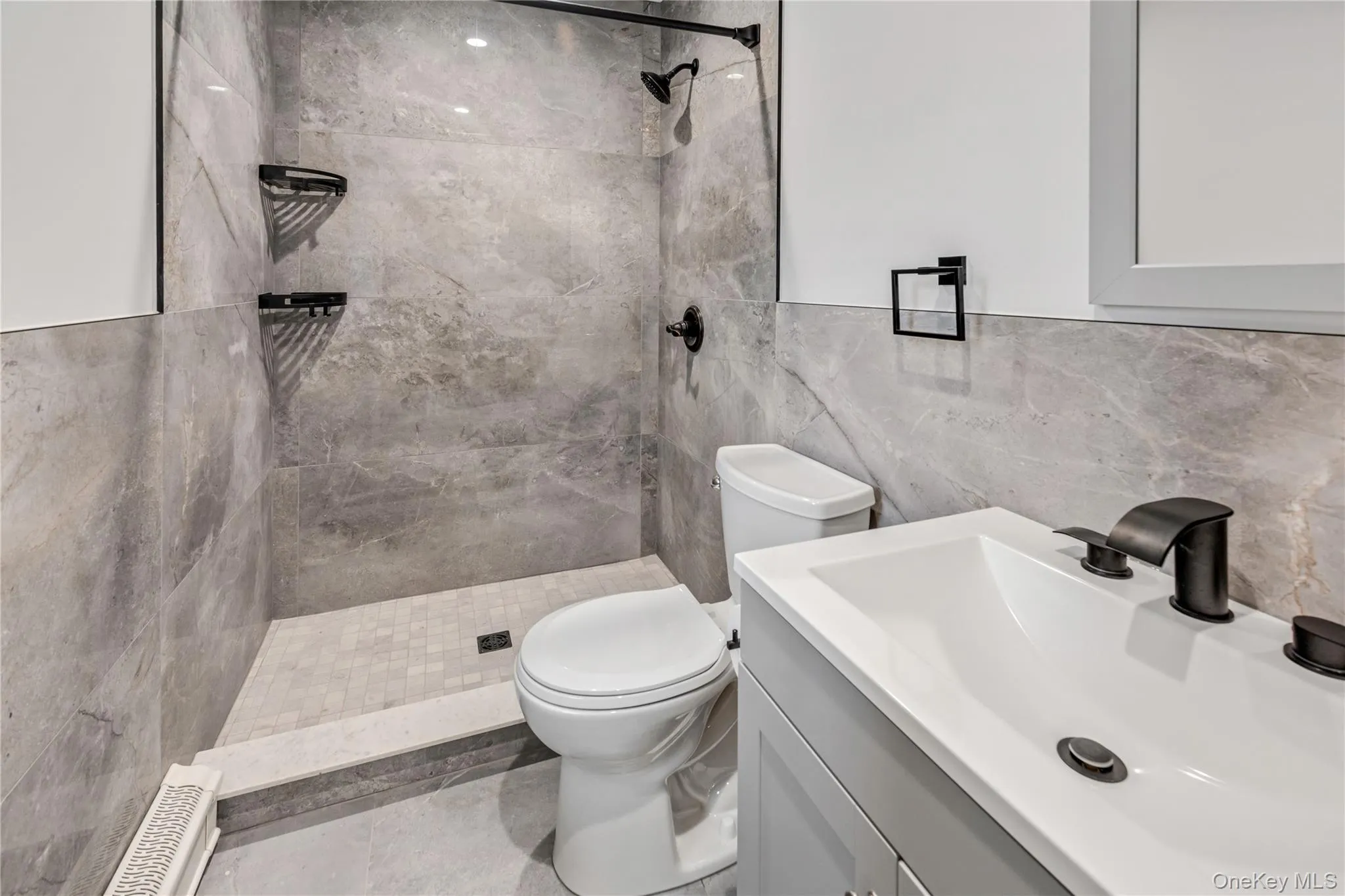 Full bathroom with tiled shower, vanity, and tile walls Full bathroom with tiled shower, vanity, and tile walls