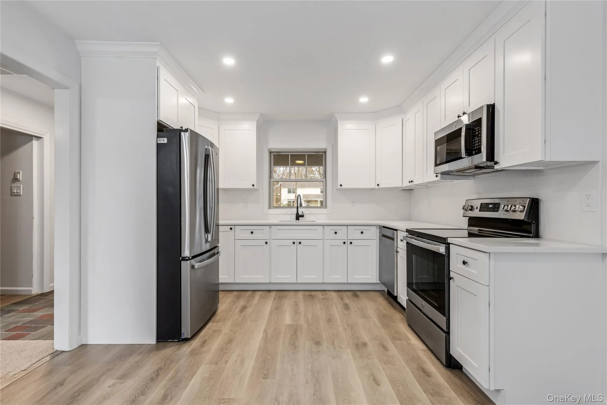 Kitchen featuring stainless steel appliances, white cabinetry, light wood-type flooring, and recessed lighting Kitchen featuring stainless steel appliances, white cabinetry, light wood-type flooring, and recessed lighting