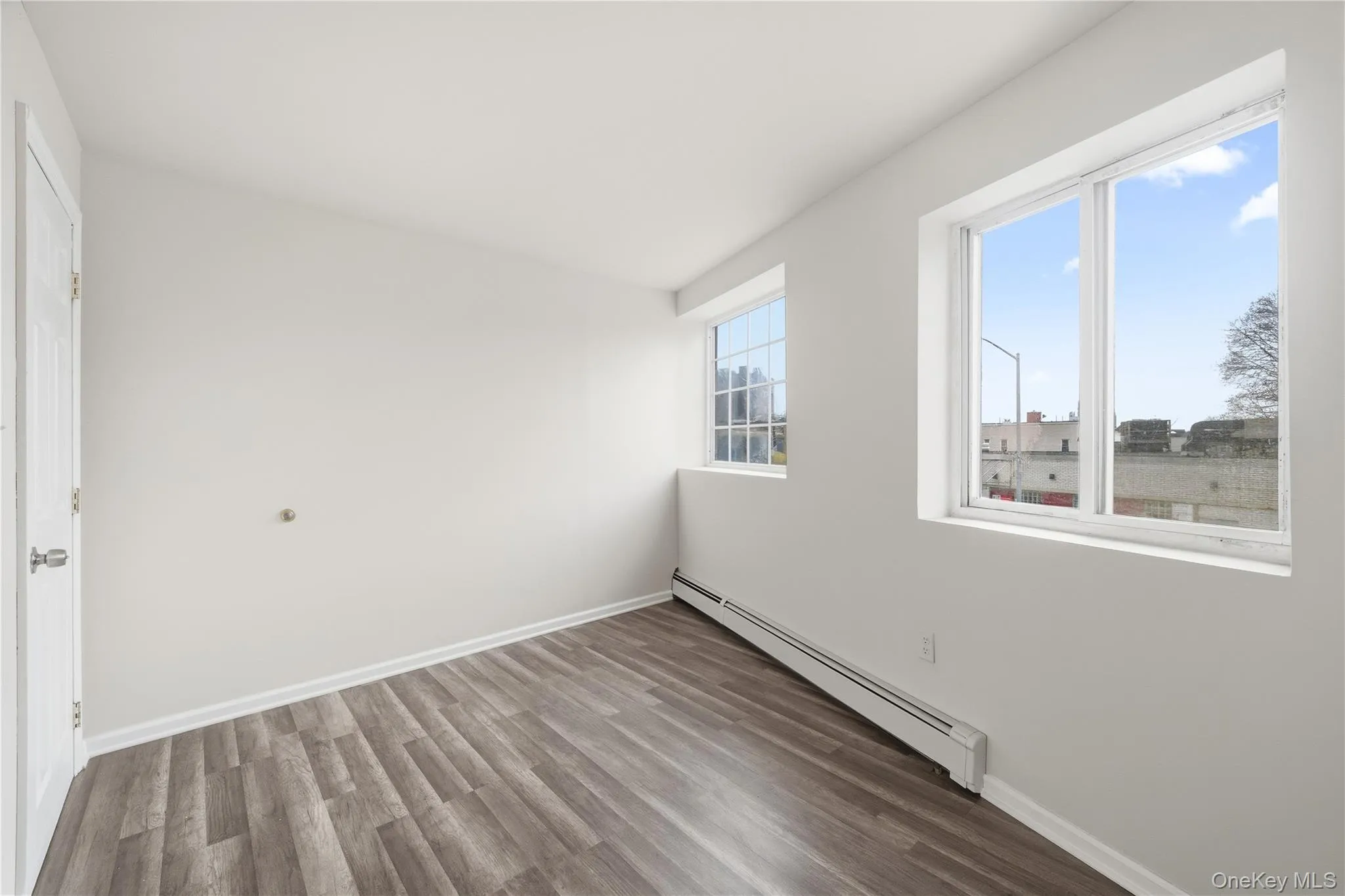 Empty room with a baseboard heating unit and wood finished floors Empty room with a baseboard heating unit and wood finished floors