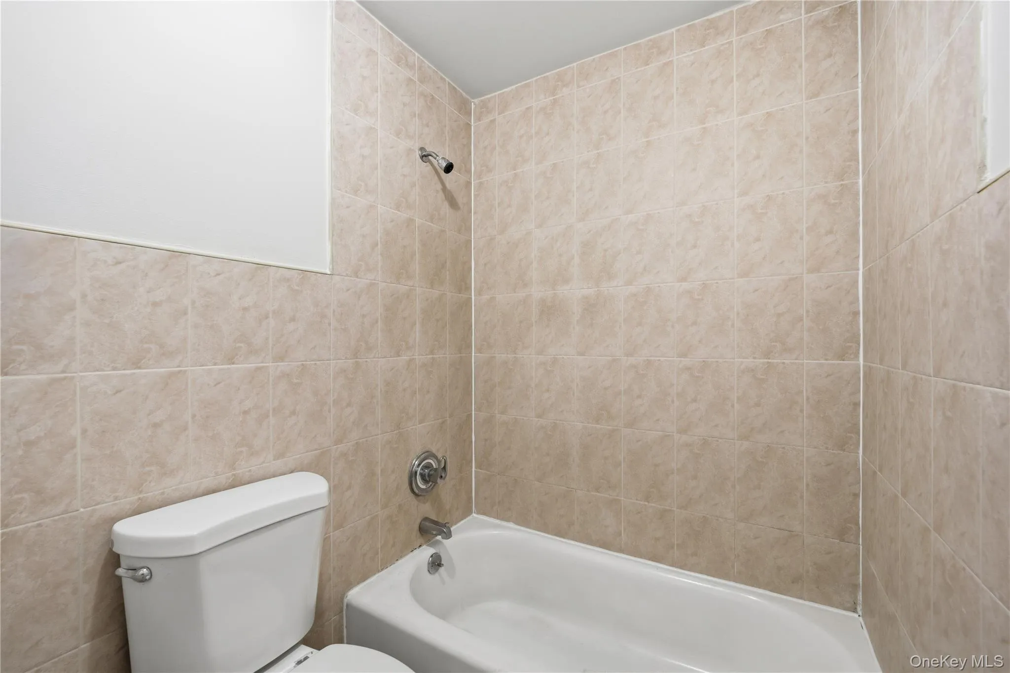 Bathroom featuring shower / washtub combination and tile walls Bathroom featuring shower / washtub combination and tile walls