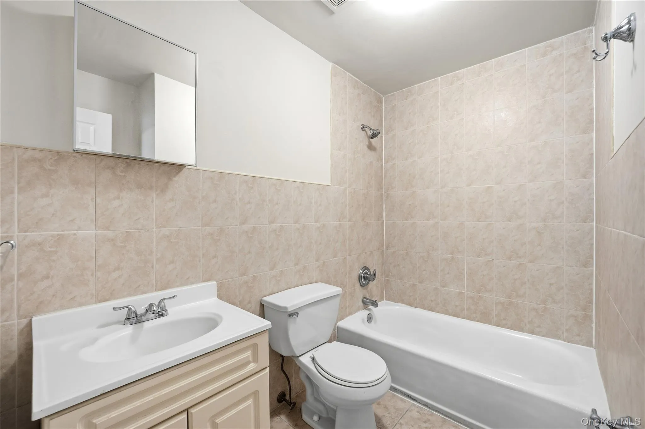 Full bathroom with tile walls, vanity, and shower / tub combination Full bathroom with tile walls, vanity, and shower / tub combination