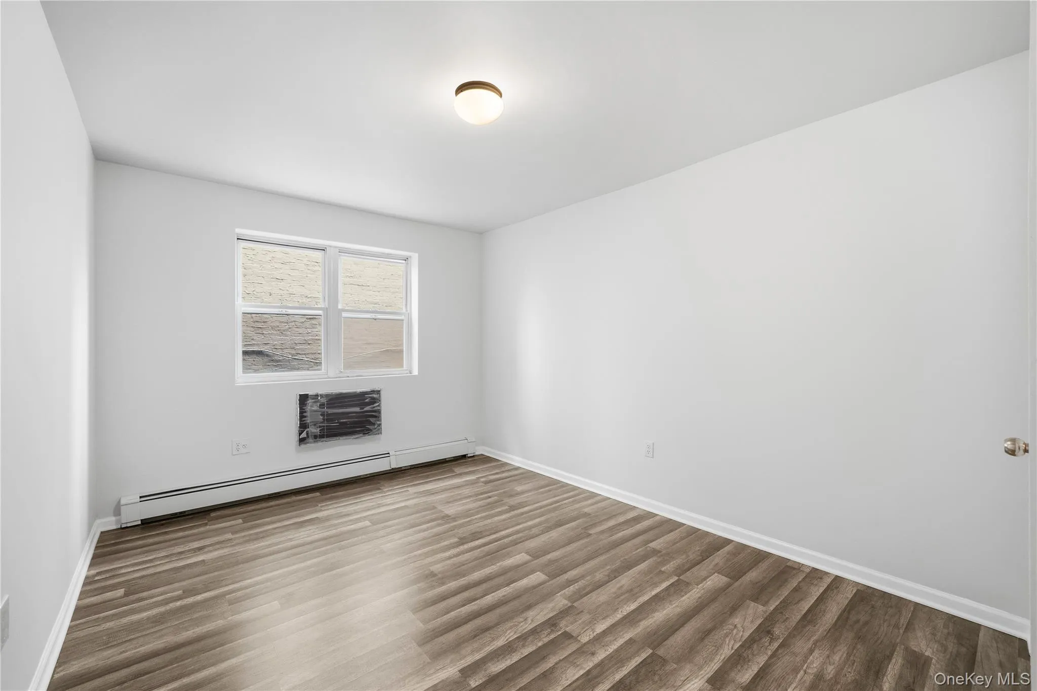 Spare room with wood finished floors and baseboard heating Spare room with wood finished floors and baseboard heating