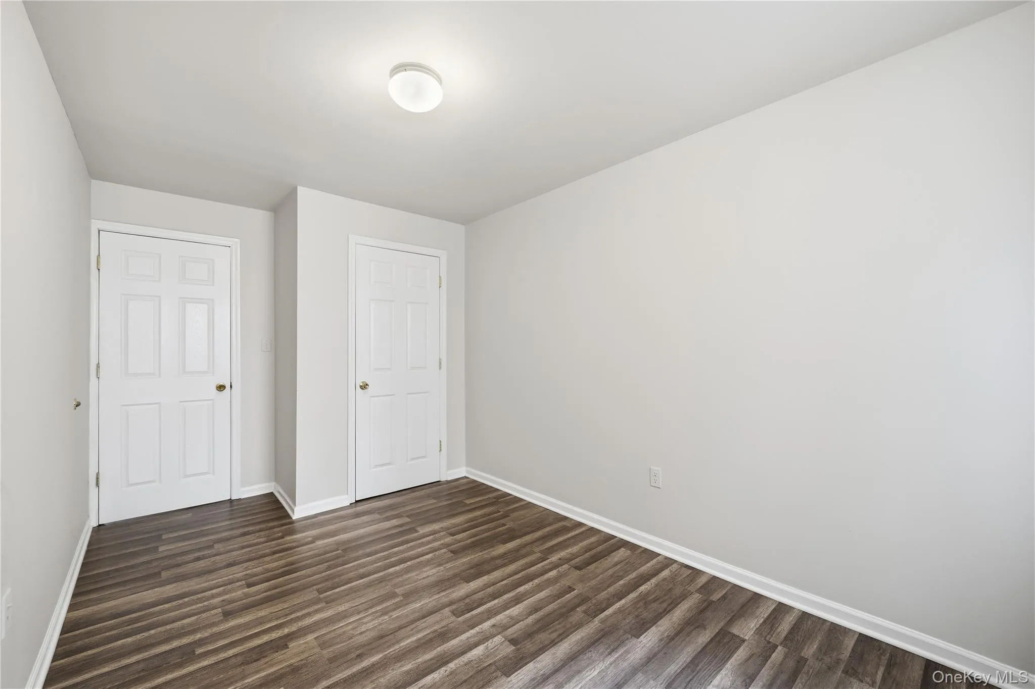 Unfurnished bedroom featuring dark wood finished floors and baseboards Unfurnished bedroom featuring dark wood finished floors and baseboards