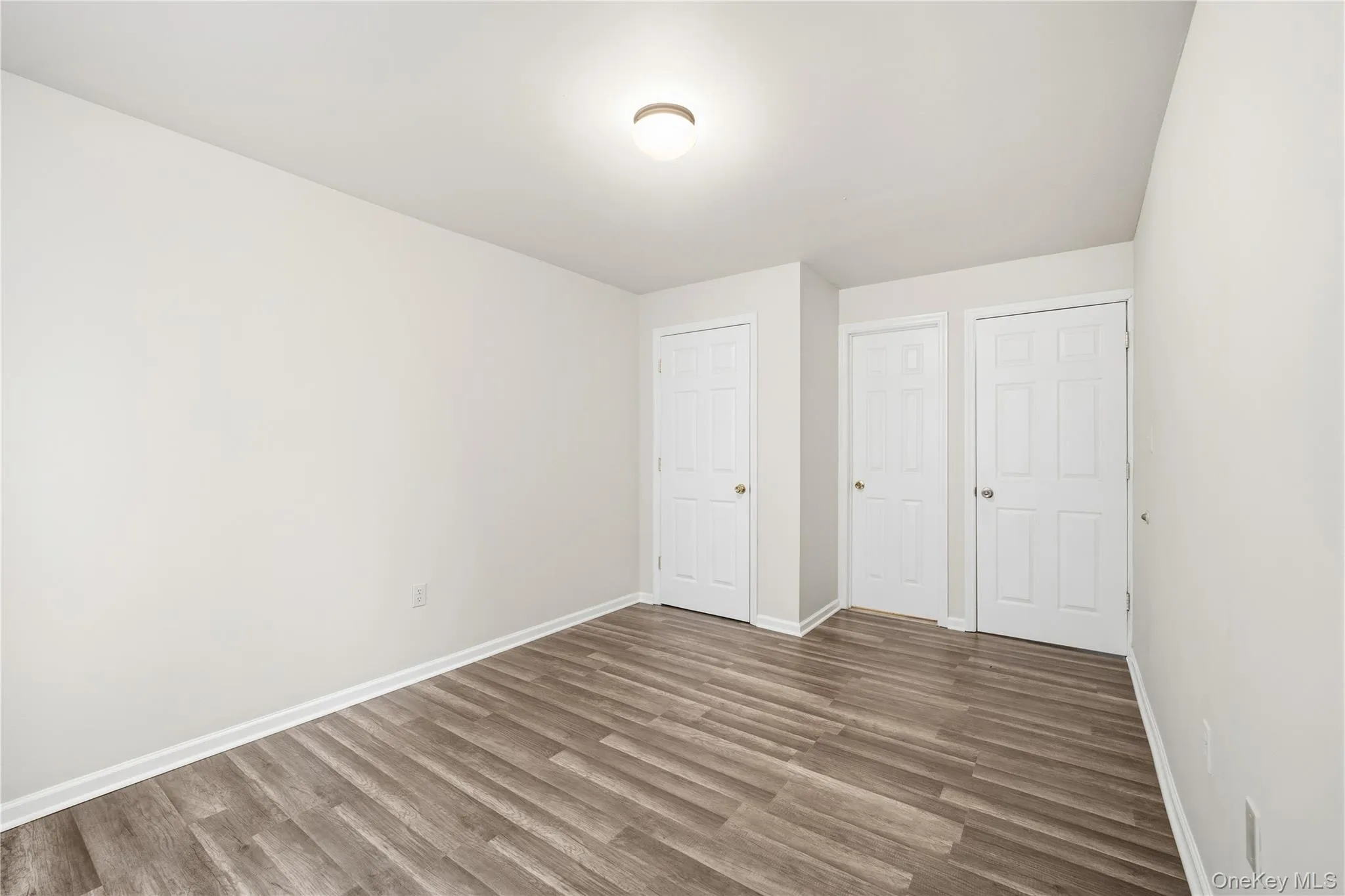 Unfurnished bedroom featuring wood finished floors and a closet Unfurnished bedroom featuring wood finished floors and a closet