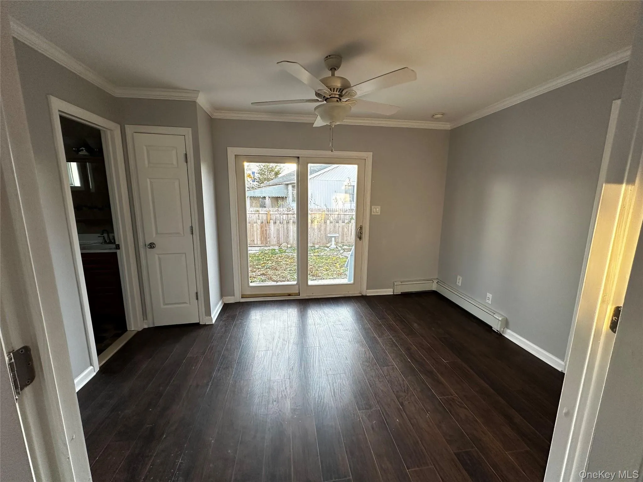Spare room featuring crown molding, dark wood finished floors, ceiling fan, and a baseboard radiator Spare room featuring crown molding, dark wood finished floors, ceiling fan, and a baseboard radiator