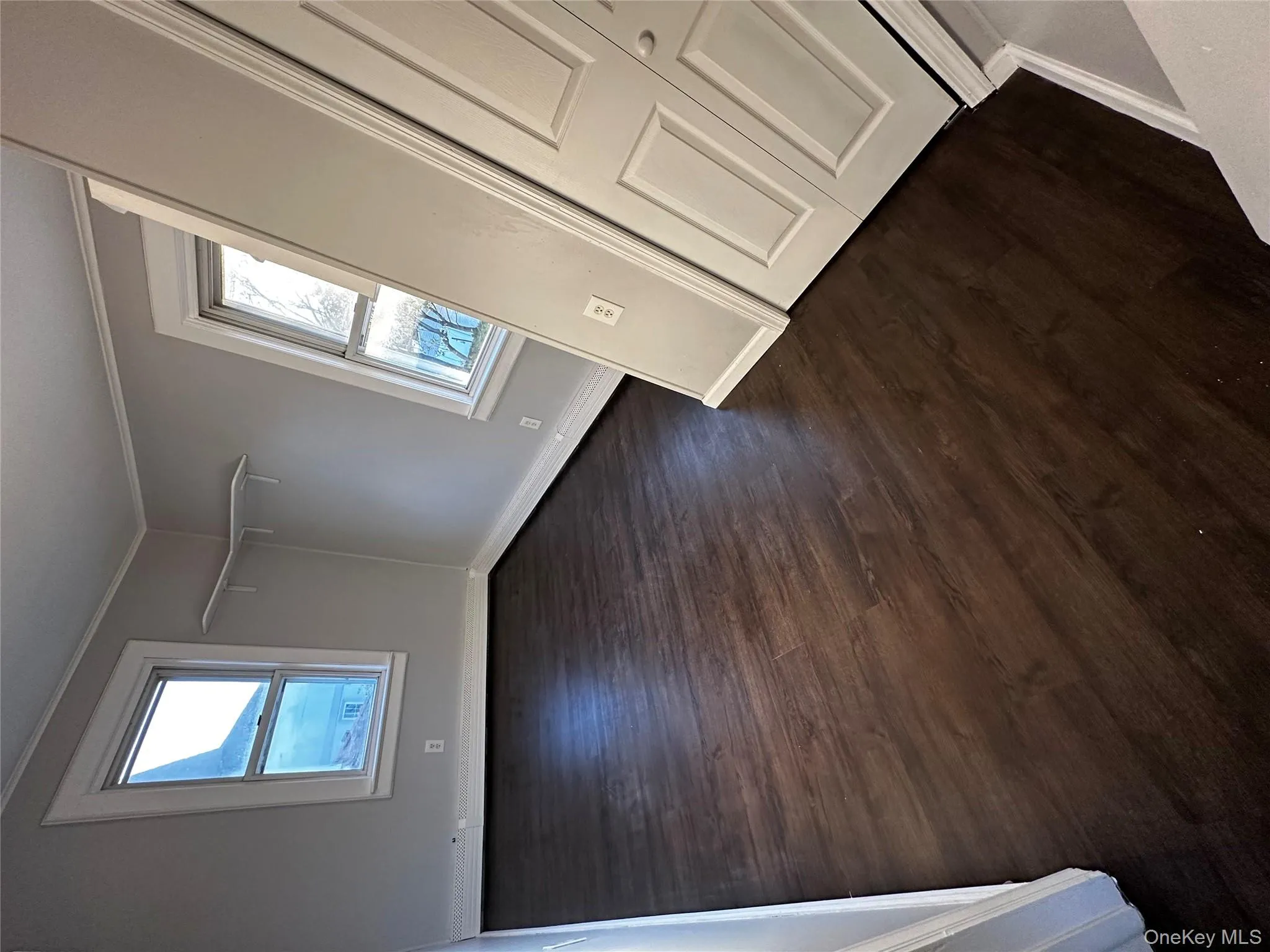 Empty room with dark wood finished floors, crown molding, and healthy amount of natural light Empty room with dark wood finished floors, crown molding, and healthy amount of natural light