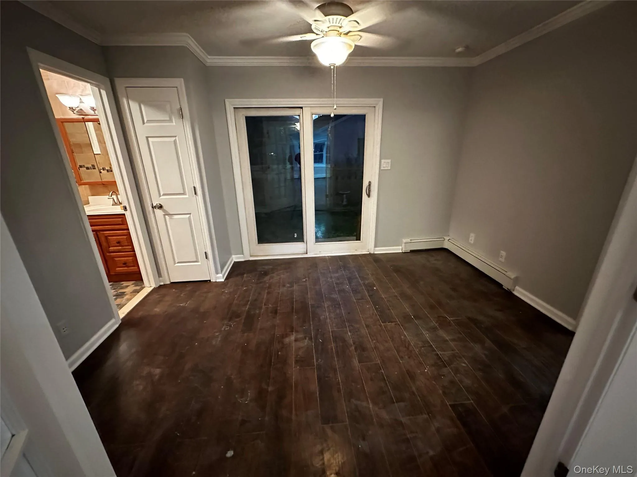Spare room with crown molding, dark wood finished floors, a ceiling fan, and baseboard heating Spare room with crown molding, dark wood finished floors, a ceiling fan, and baseboard heating
