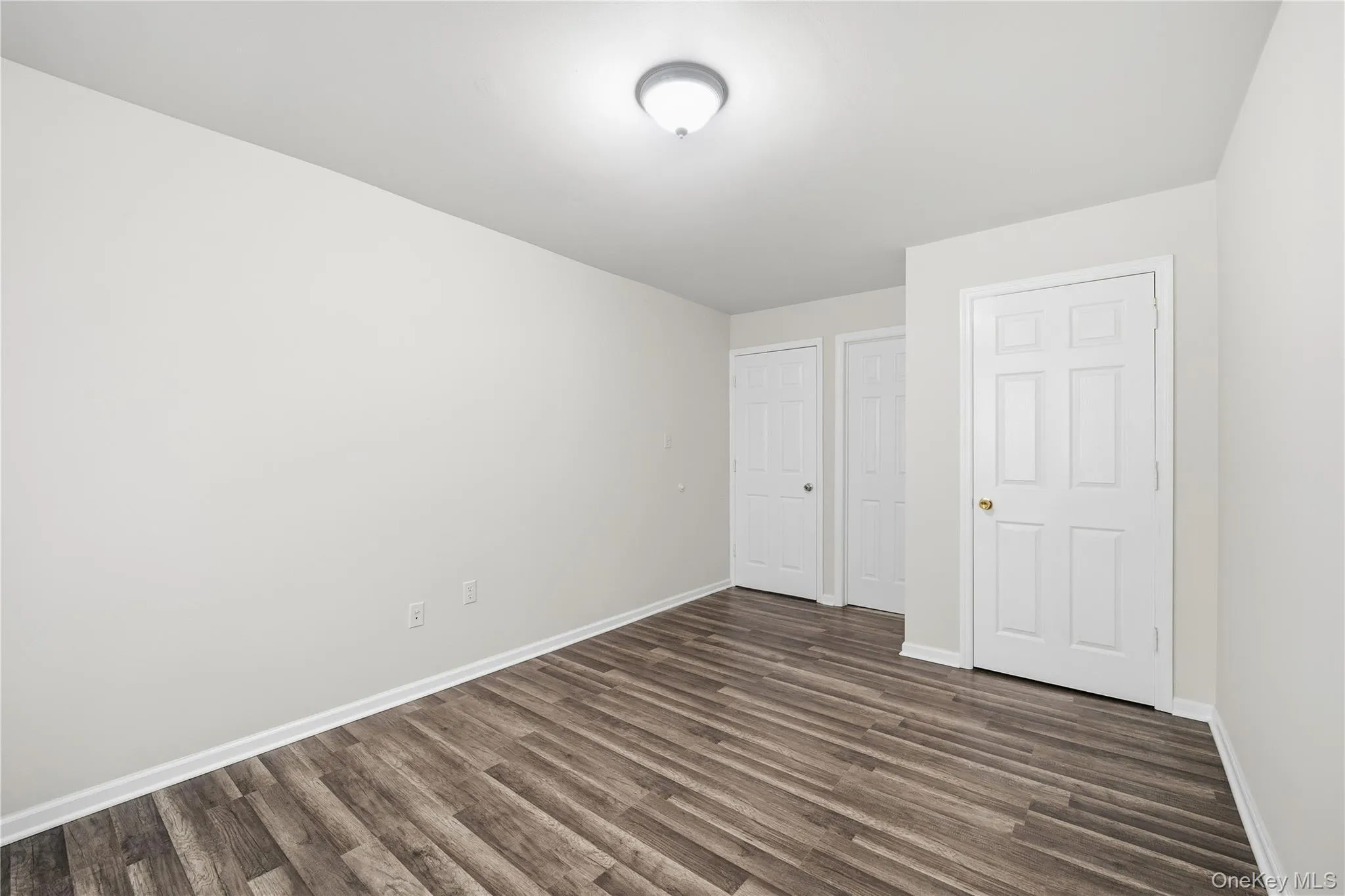 Unfurnished bedroom featuring dark wood-style floors and baseboards Unfurnished bedroom featuring dark wood-style floors and baseboards