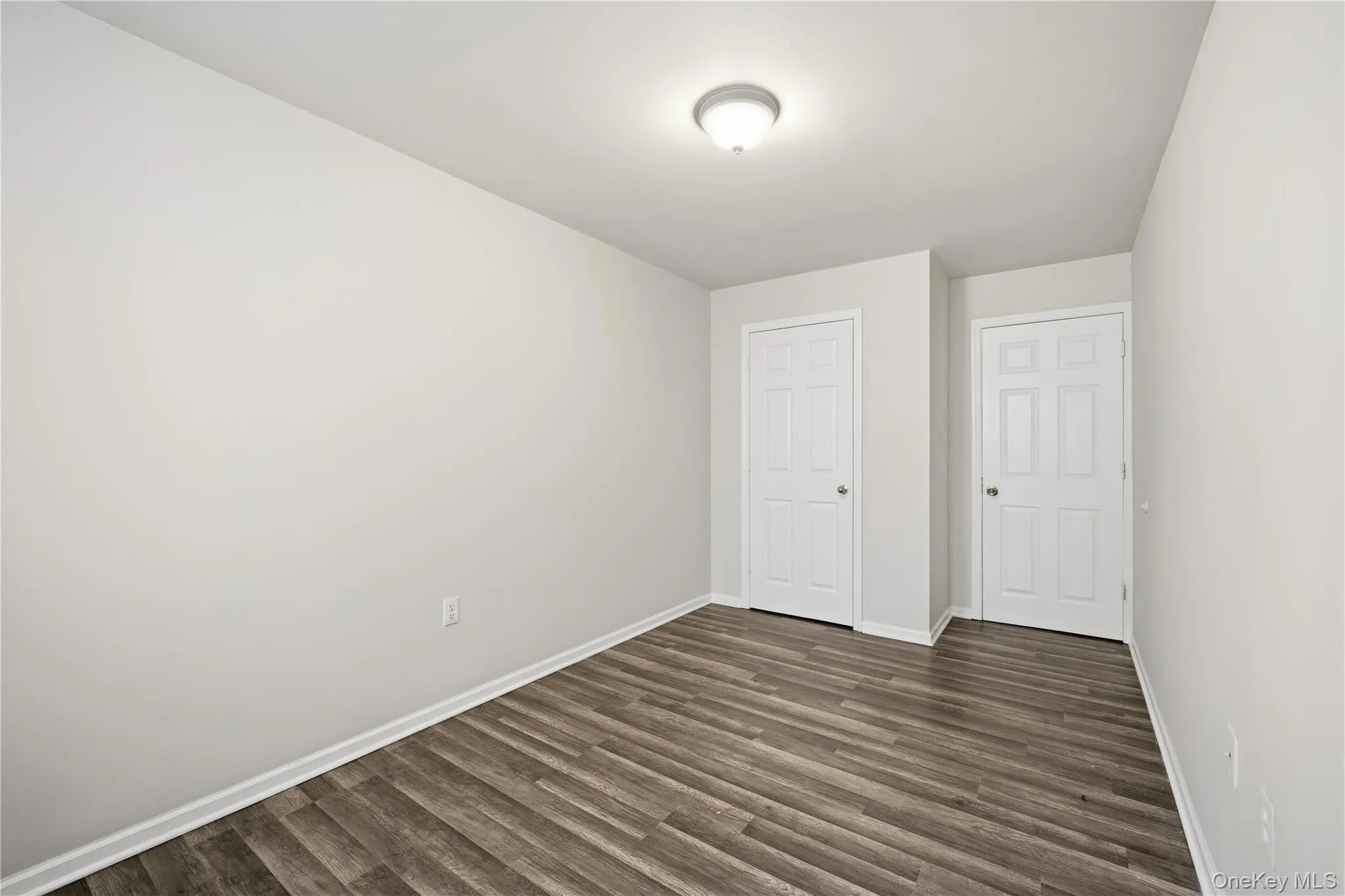 Unfurnished bedroom featuring dark wood-type flooring and baseboards Unfurnished bedroom featuring dark wood-type flooring and baseboards