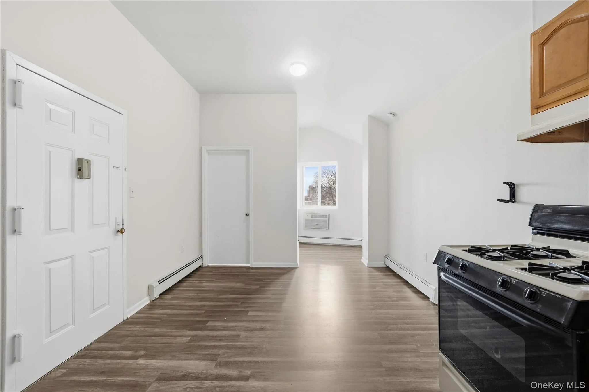 Kitchen featuring black range with gas stovetop, dark wood-style floors, a baseboard radiator, and lofted ceiling Kitchen featuring black range with gas stovetop, dark wood-style floors, a baseboard radiator, and lofted ceiling