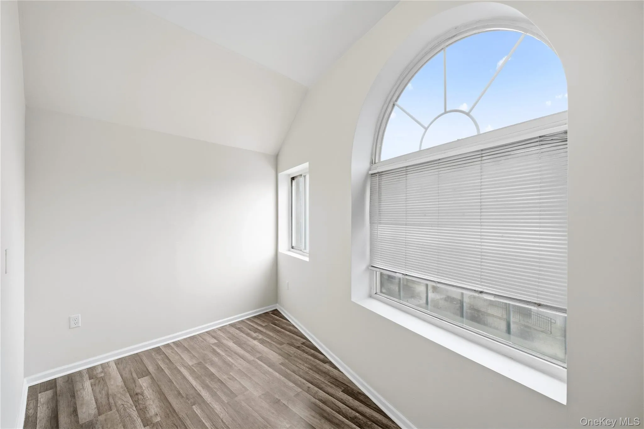 Empty room with lofted ceiling and wood finished floors Empty room with lofted ceiling and wood finished floors