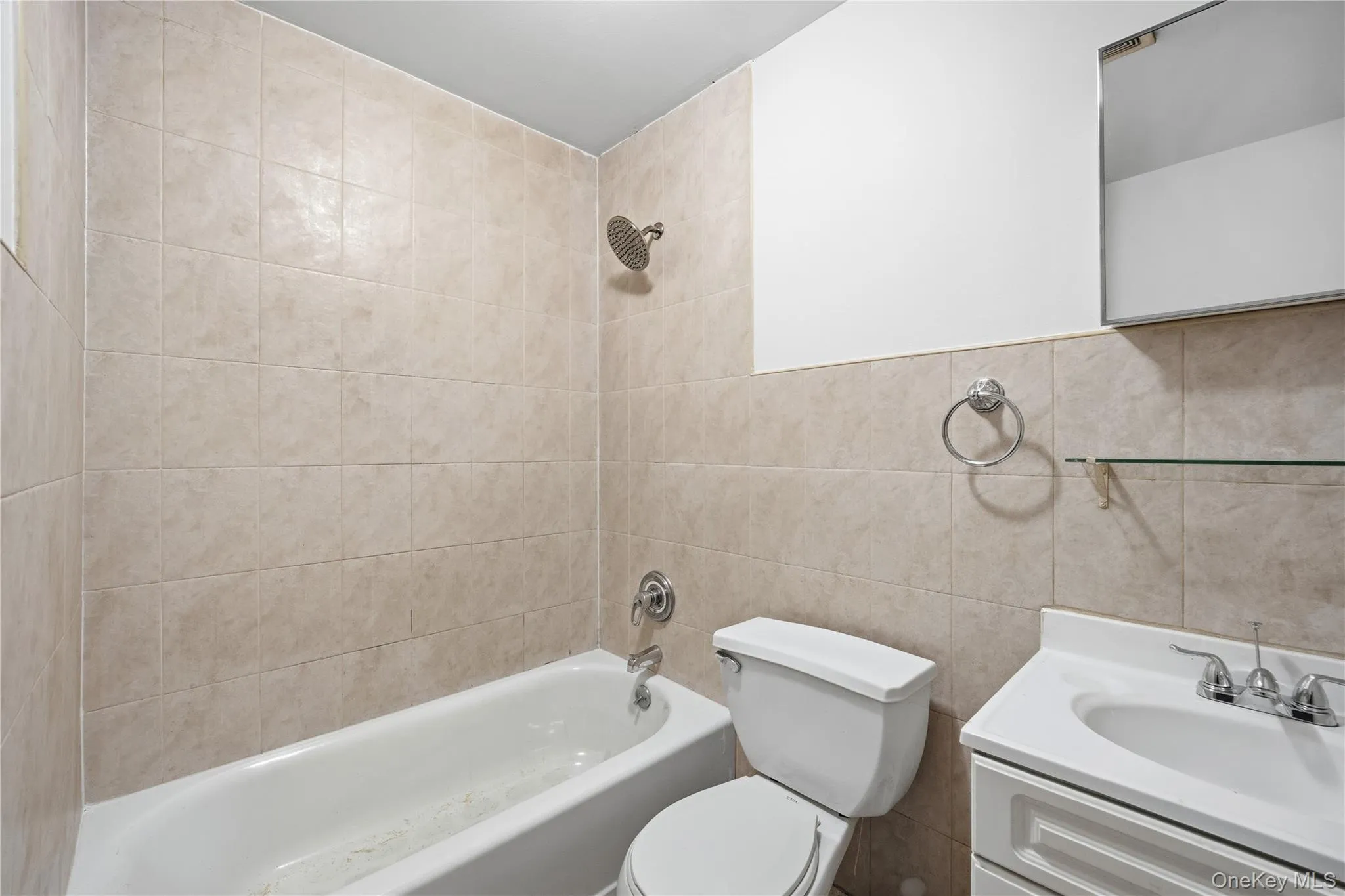 Bathroom featuring vanity, shower / washtub combination, and tile walls Bathroom featuring vanity, shower / washtub combination, and tile walls