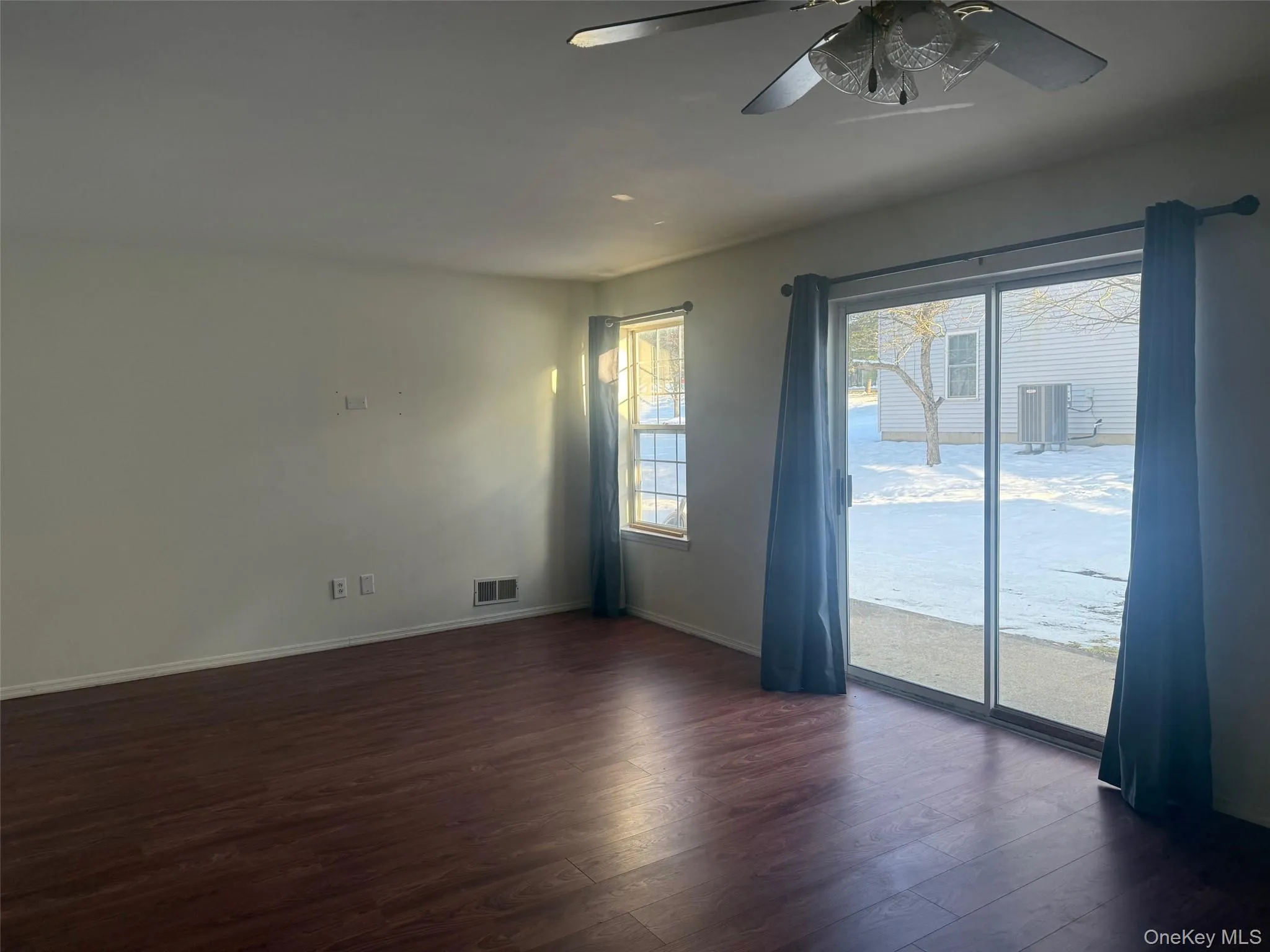 Empty room with dark wood finished floors and a ceiling fan Empty room with dark wood finished floors and a ceiling fan
