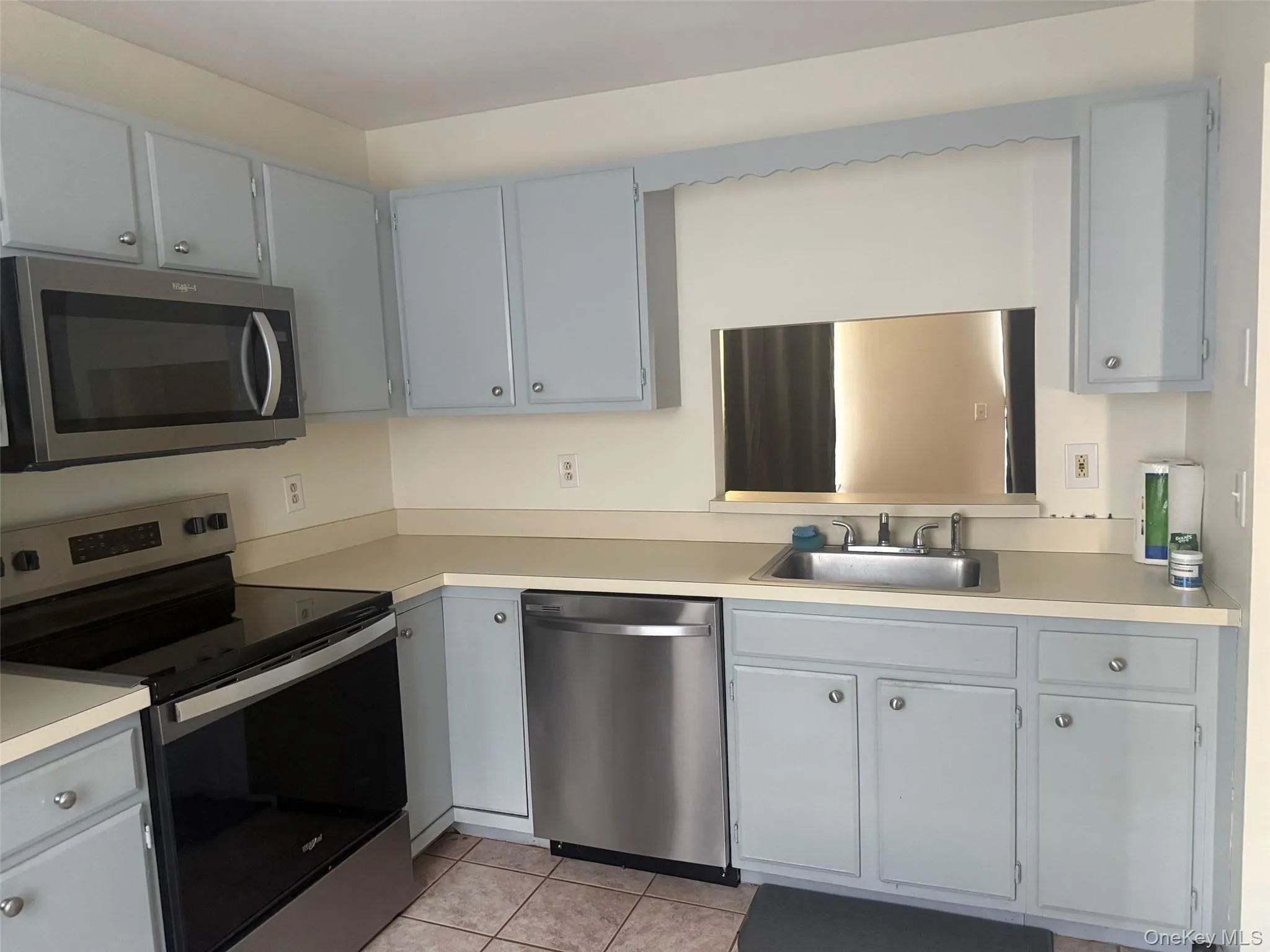 Kitchen featuring appliances with stainless steel finishes, light countertops, gray cabinetry, and light tile patterned floors Kitchen featuring appliances with stainless steel finishes, light countertops, gray cabinetry, and light tile patterned floors