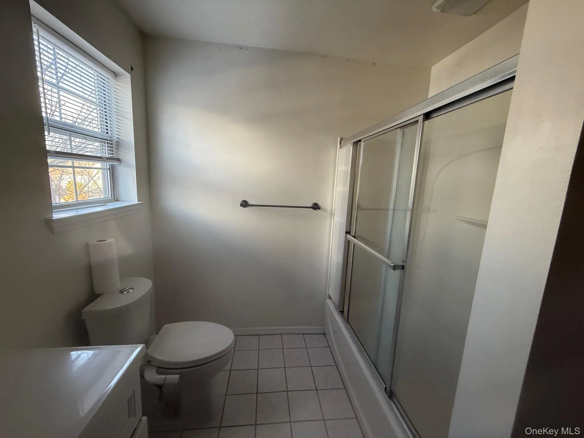 Bathroom with vanity, light tile patterned flooring, and combined bath / shower with glass door Bathroom with vanity, light tile patterned flooring, and combined bath / shower with glass door