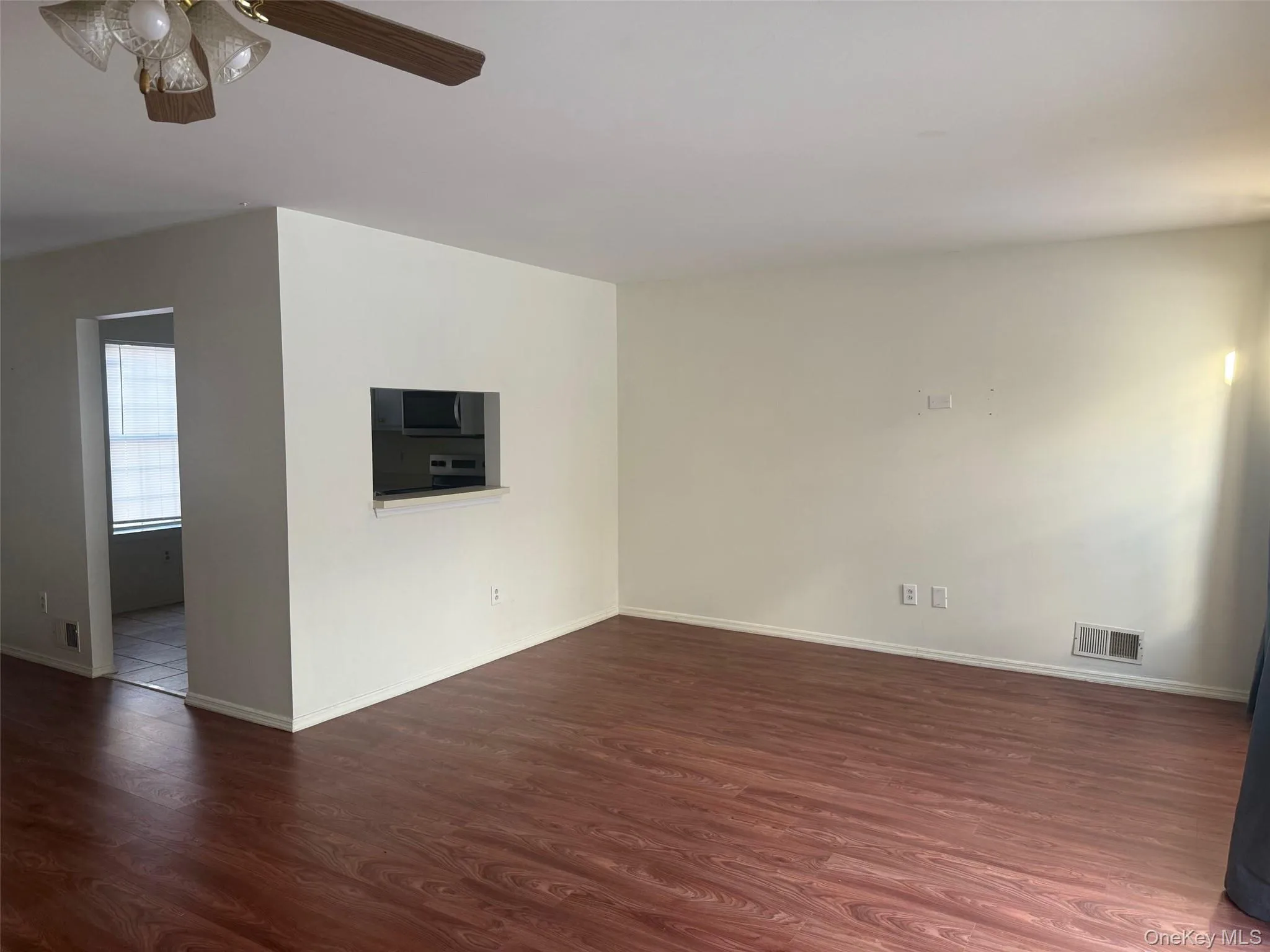 Empty room with dark wood-style floors and a ceiling fan Empty room with dark wood-style floors and a ceiling fan