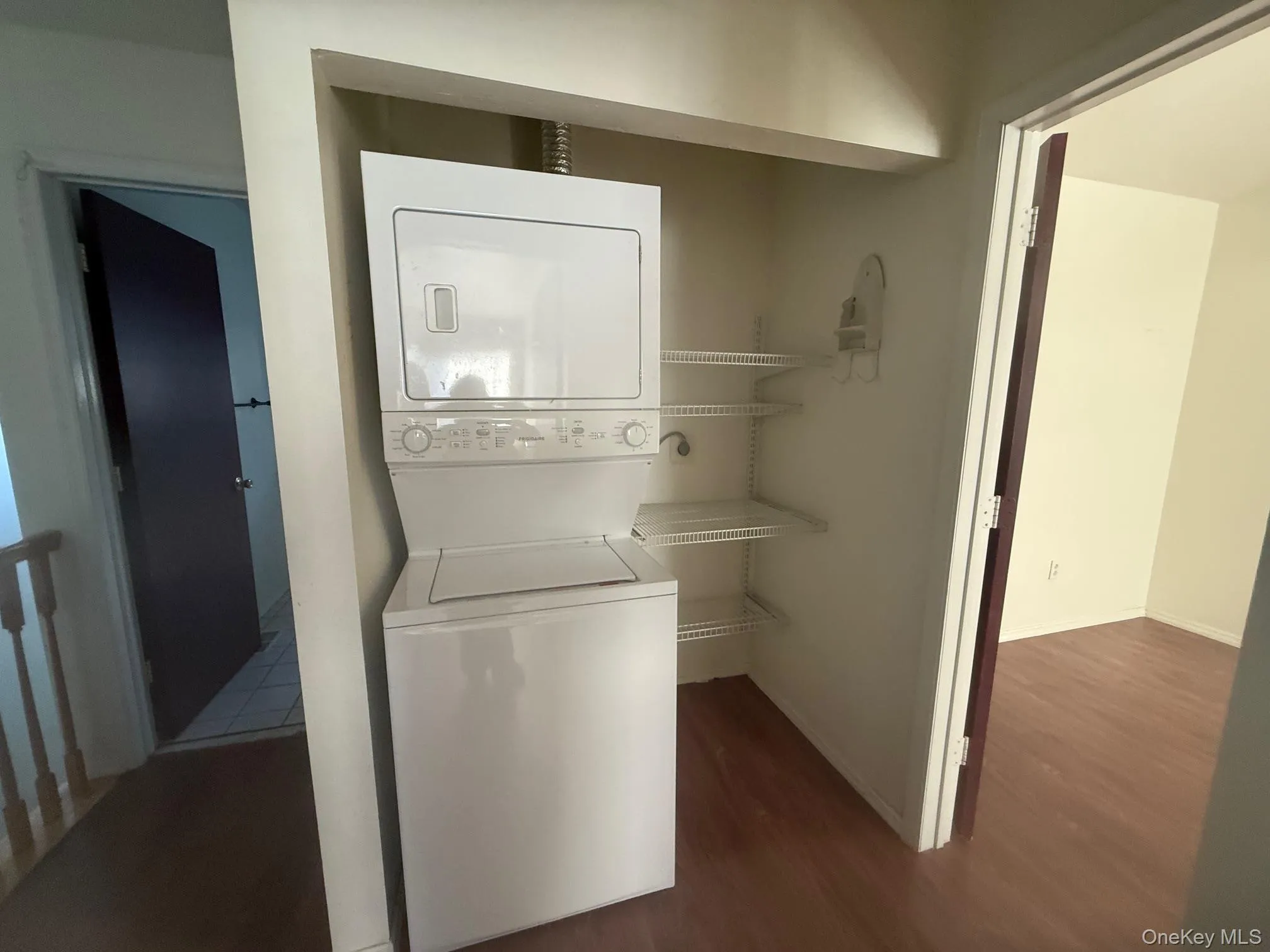 Upstairs Laundry room with dark wood-style flooring and stacked washer / dryer Upstairs Laundry room with dark wood-style flooring and stacked washer / dryer