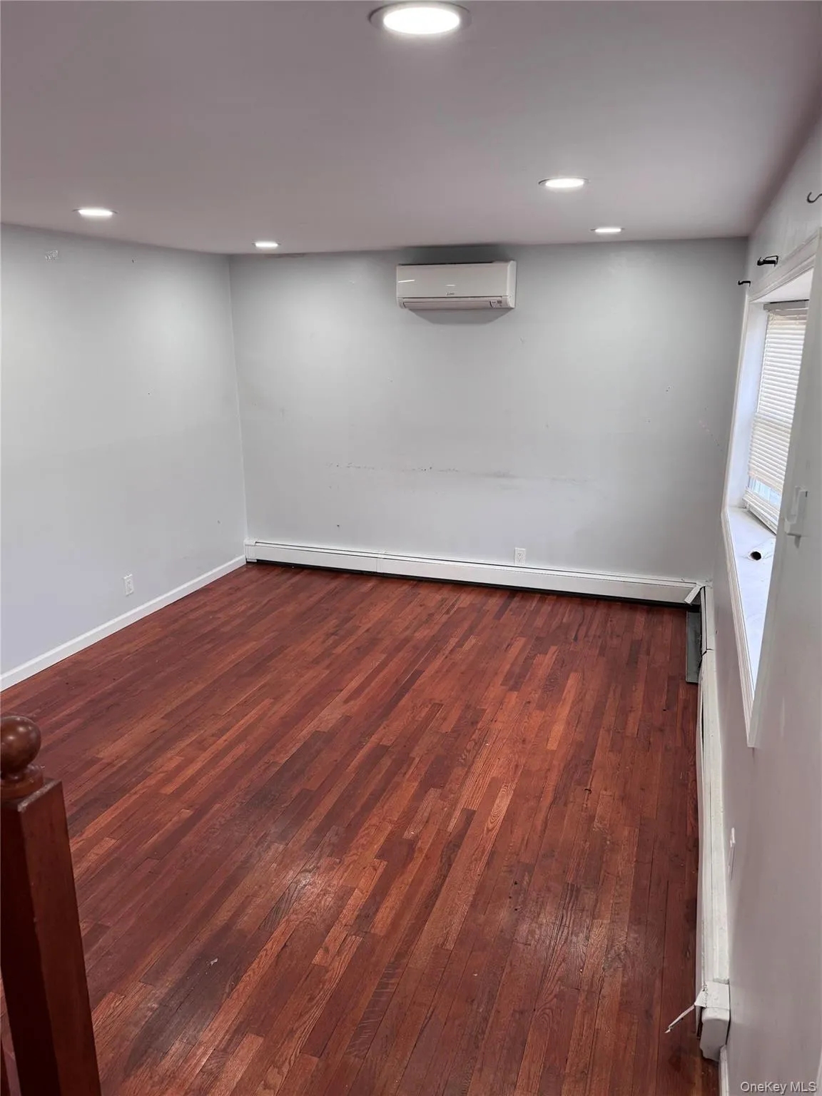 Empty room with dark wood-style flooring, a wall mounted air conditioner, baseboard heating, and recessed lighting Empty room with dark wood-style flooring, a wall mounted air conditioner, baseboard heating, and recessed lighting