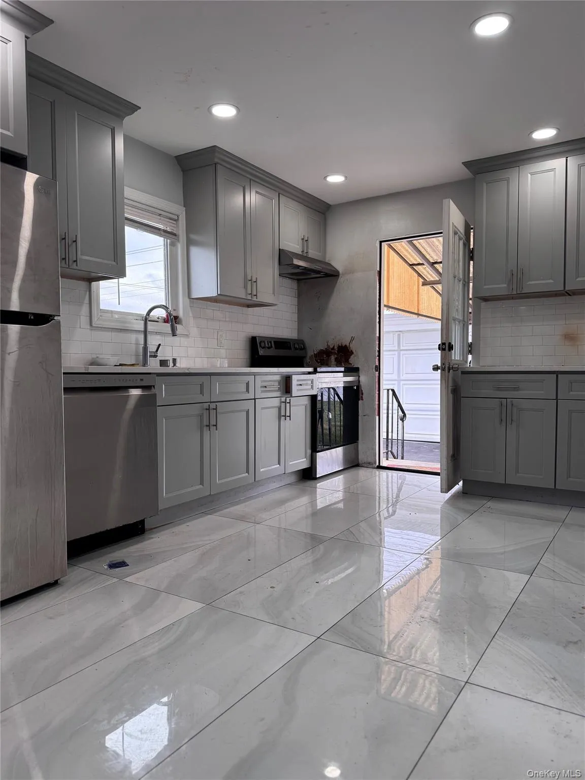 Kitchen with gray cabinets, appliances with stainless steel finishes, light marble finish flooring, and recessed lighting Kitchen with gray cabinets, appliances with stainless steel finishes, light marble finish flooring, and recessed lighting