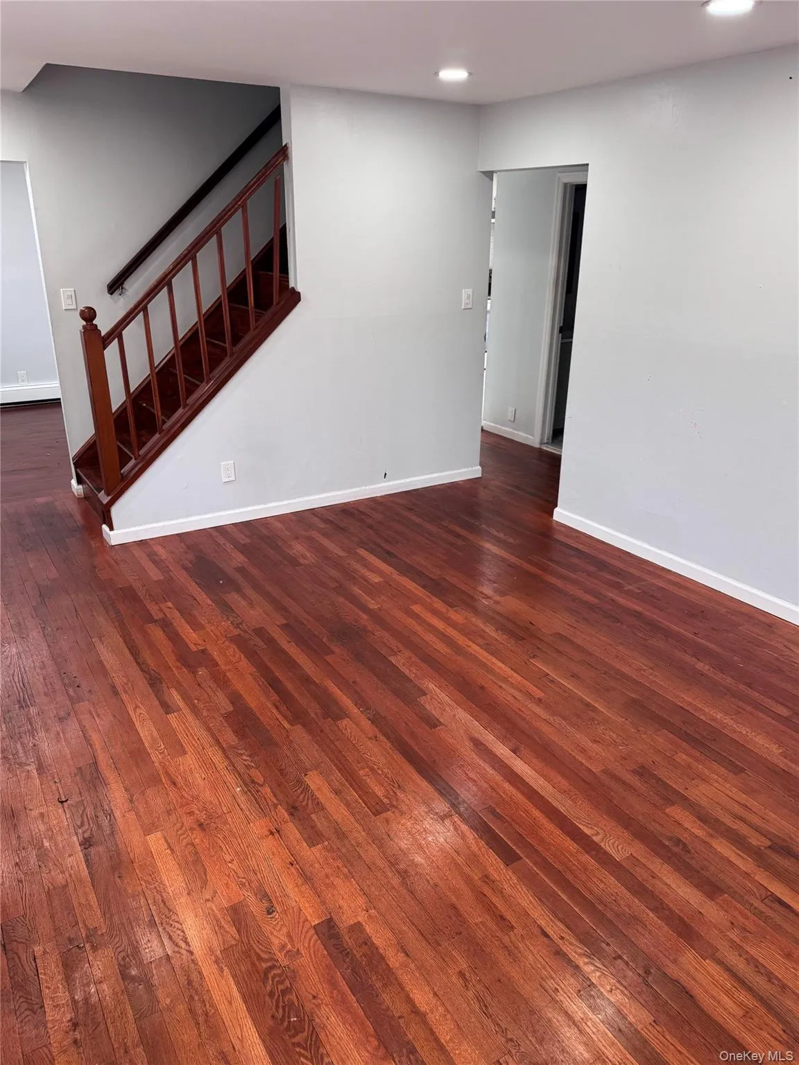 Unfurnished living room featuring dark wood finished floors, stairs, and recessed lighting Unfurnished living room featuring dark wood finished floors, stairs, and recessed lighting