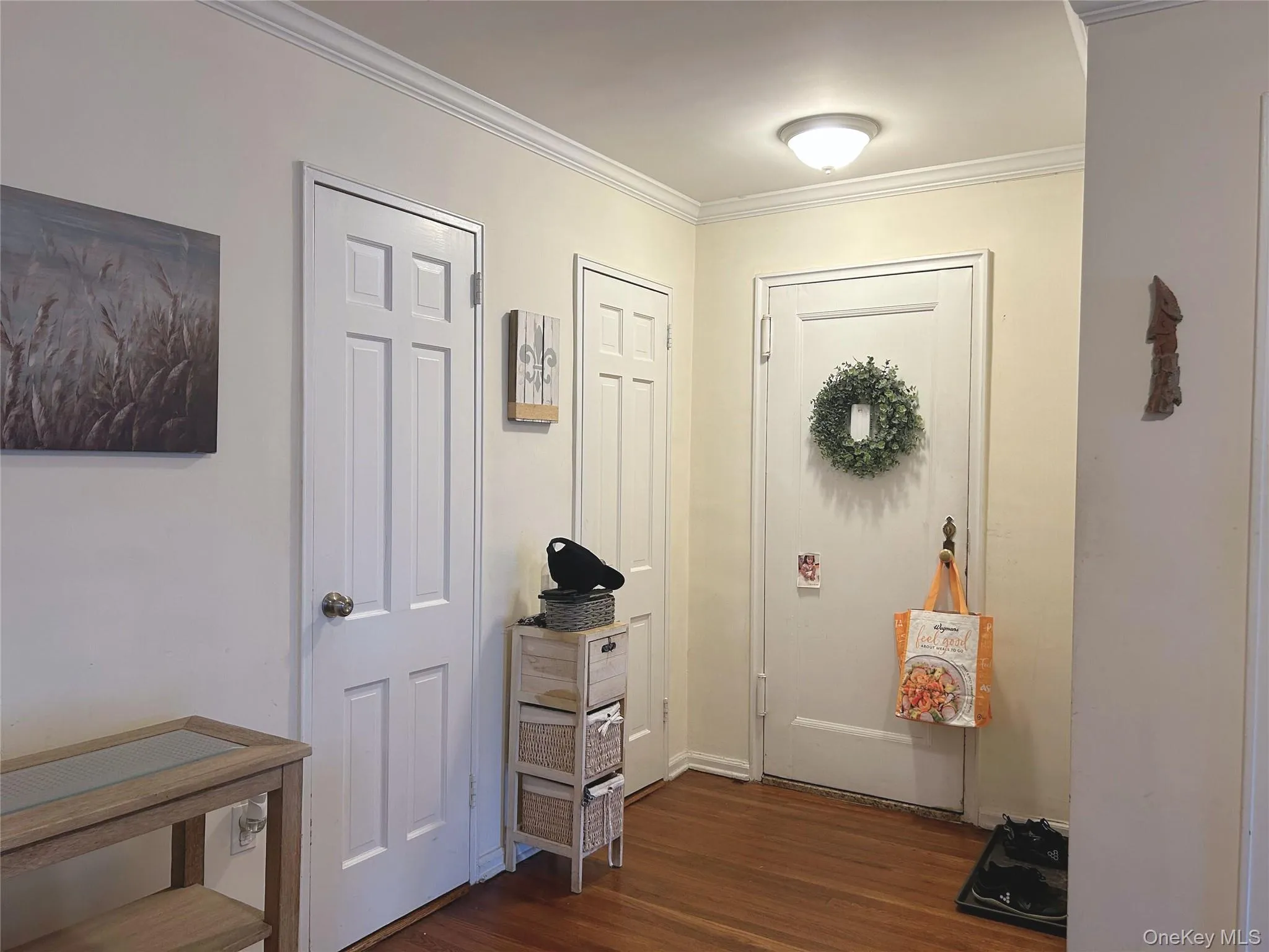 Doorway to outside with wood finished floors and ornamental molding Doorway to outside with wood finished floors and ornamental molding