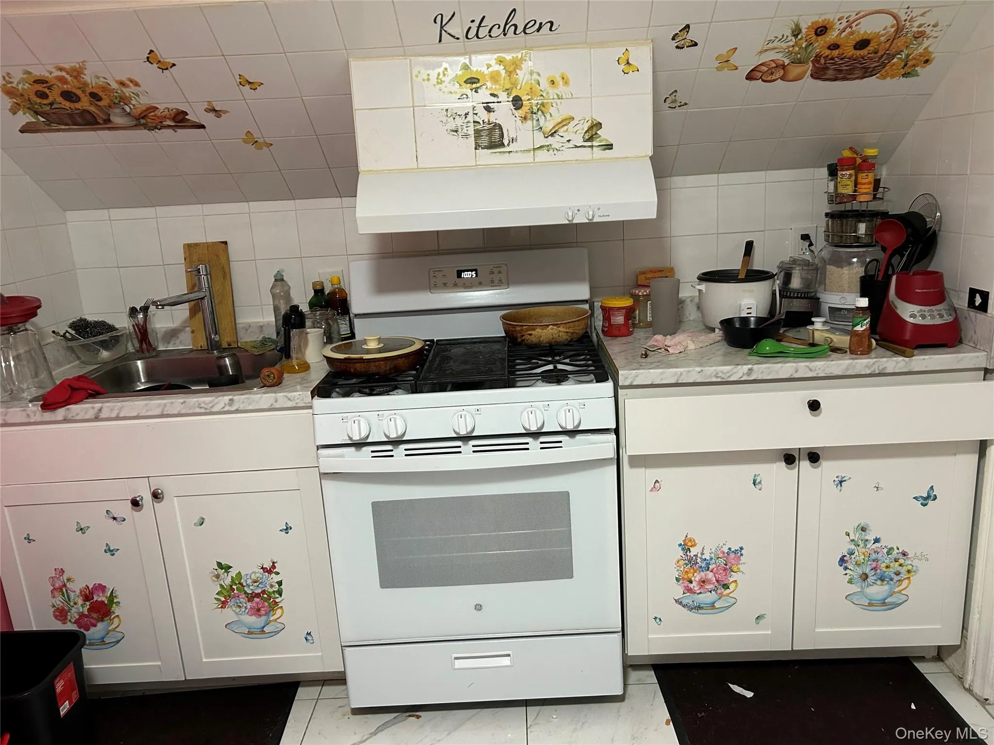 Kitchen featuring white gas range oven, white cabinetry, light countertops, extractor fan, and tasteful backsplash Kitchen featuring white gas range oven, white cabinetry, light countertops, extractor fan, and tasteful backsplash