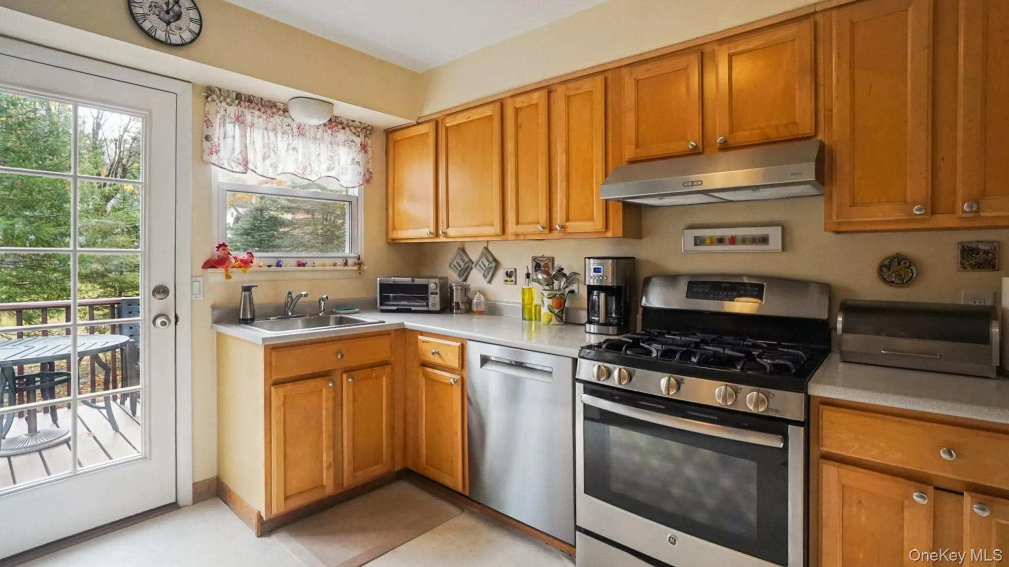 Kitchen featuring appliances with stainless steel finishes, brown cabinets, and under cabinet range hood Kitchen featuring appliances with stainless steel finishes, brown cabinets, and under cabinet range hood
