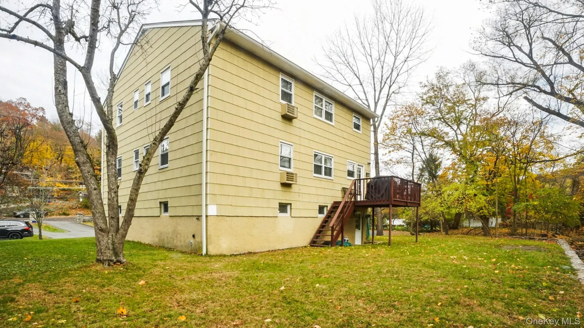 Rear view of property featuring a lawn, stairway, and a wooden deck Rear view of property featuring a lawn, stairway, and a wooden deck