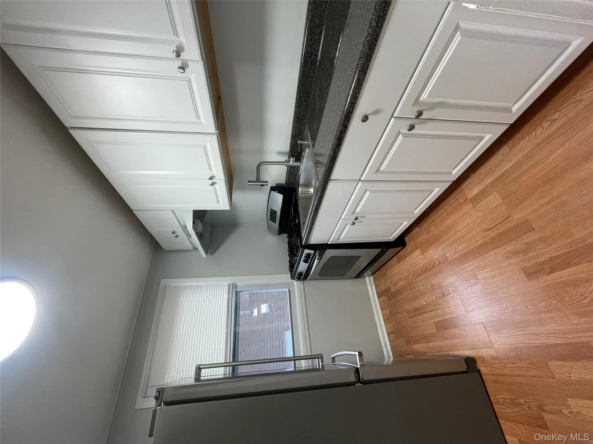 Kitchen featuring refrigerator, white cabinets, stainless steel range with gas cooktop, and dark stone counters Kitchen featuring refrigerator, white cabinets, stainless steel range with gas cooktop, and dark stone counters